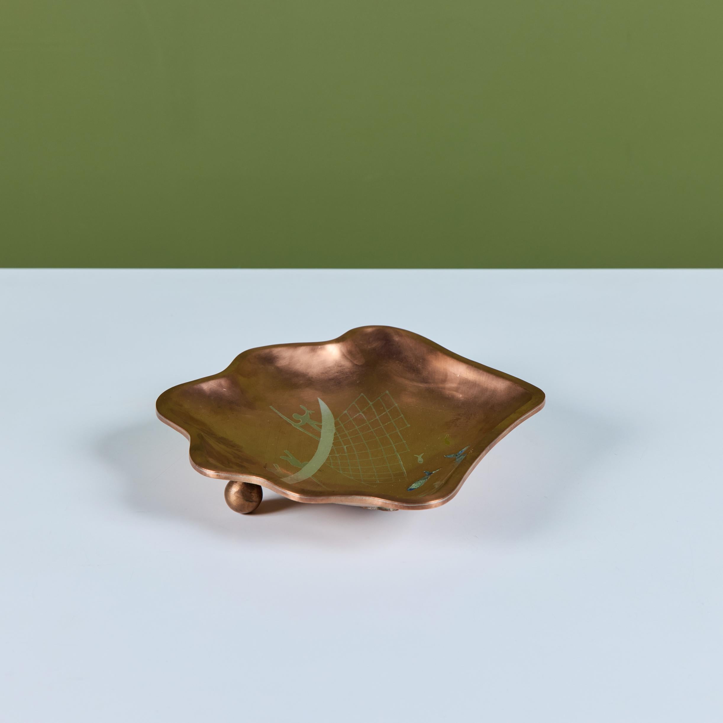 Piatto di fabbricazione messicana, anni '60 circa, composto da rame, ottone e argento. La sua forma libera mostra una scena di pesca con tre pesci intarsiati con rocce turchesi e blu. Poggia su due piedi a sfera in rame. Timbro Taxco Mexico - Los