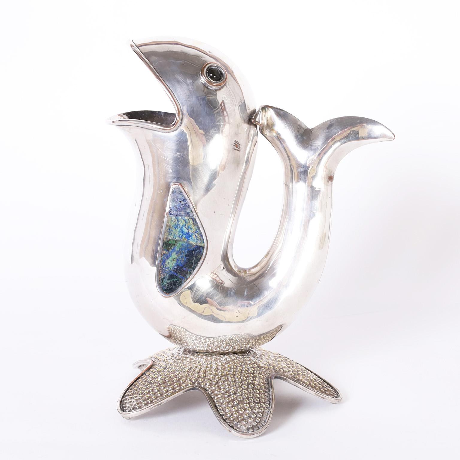 Whimsical mid-century silver plate on copper fish form water pitcher crafted by a master silversmith with stone eyes and fins on a starfish base. Signed Los Castillo Mexico on the bottom.