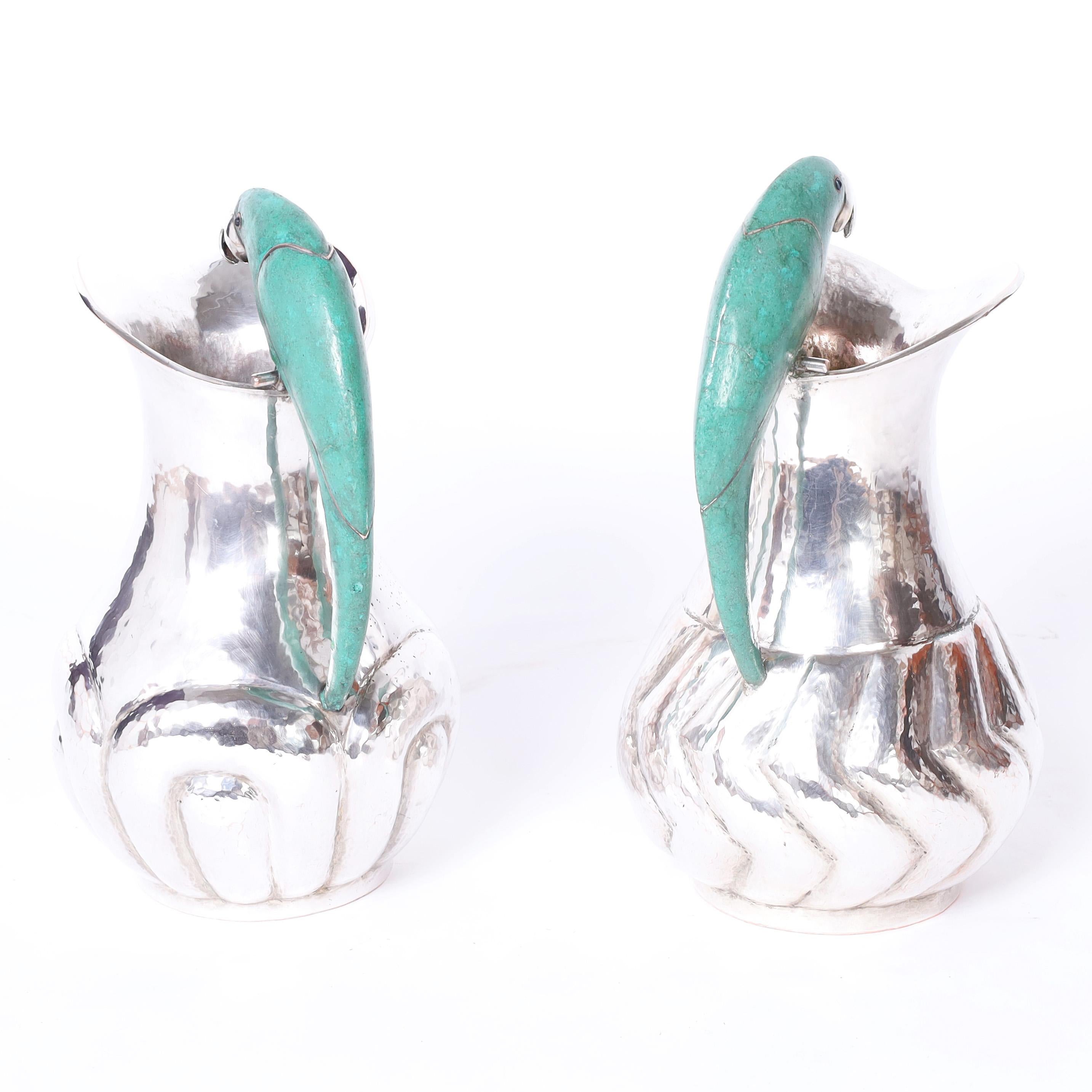 Standout near pair of pitchers hand crafted in hammered copper under silver plate in modern form featuring stone clad stylized parrots as handles. Stamped Mexico on the bottoms.