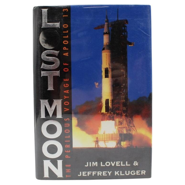Lovell, Jim y Jeffrey Kluger.  Luna perdida: El peligroso viaje del Apolo 13. Boston: Houghton Mifflin Company, 1994. Octavo. Cartoné original de tela azul, lomo negro con títulos plateados, sobrecubierta original sin recortar. Pegatina firmada por