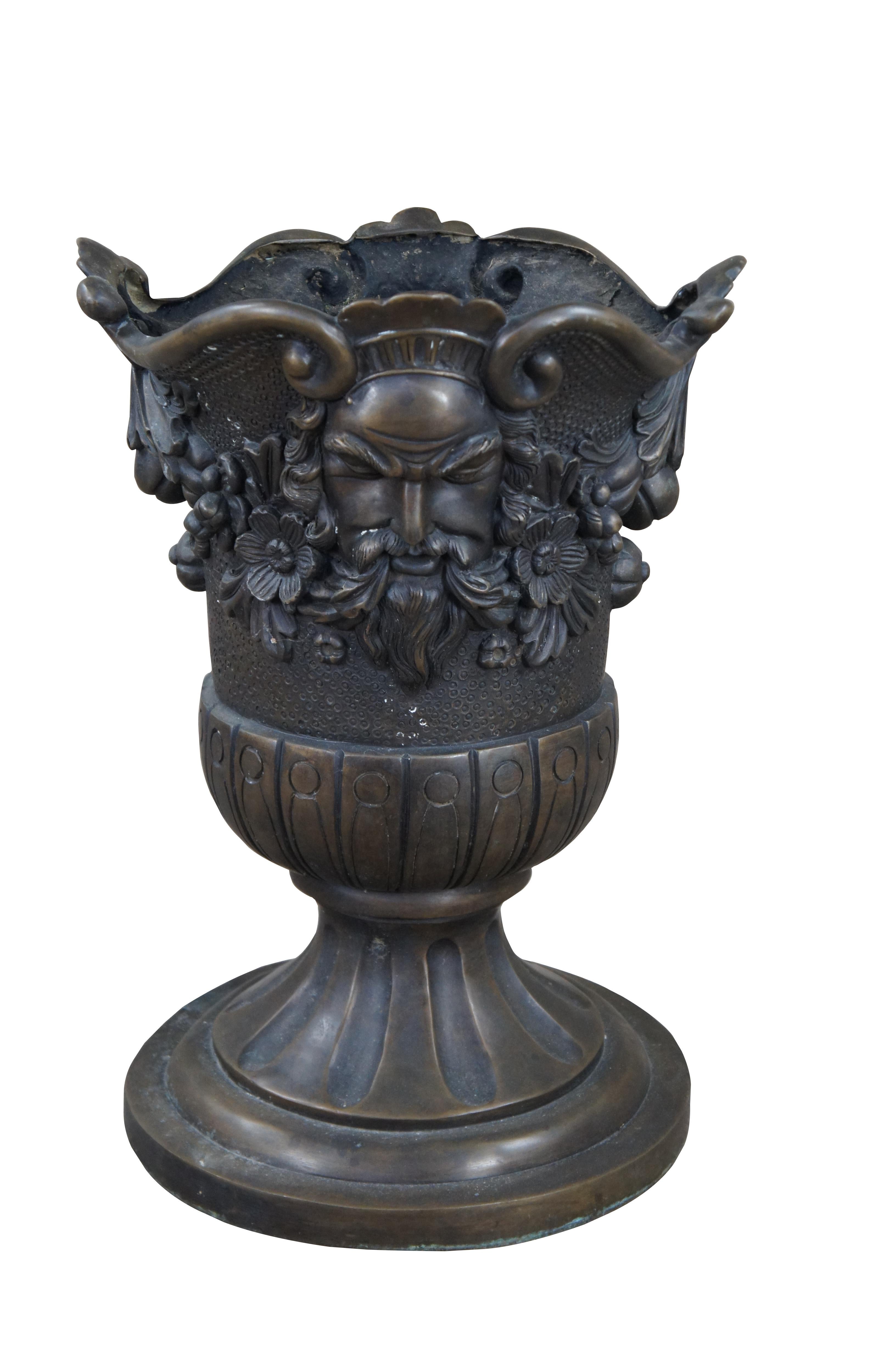 A beautiful figured bronze urn or planter. Features a traditional Grecian form with a lobed body and round fluted base. Decorated with a low relief depiction of Zeus flanking opposite sides amongst foliate and floral detail. Great for display around