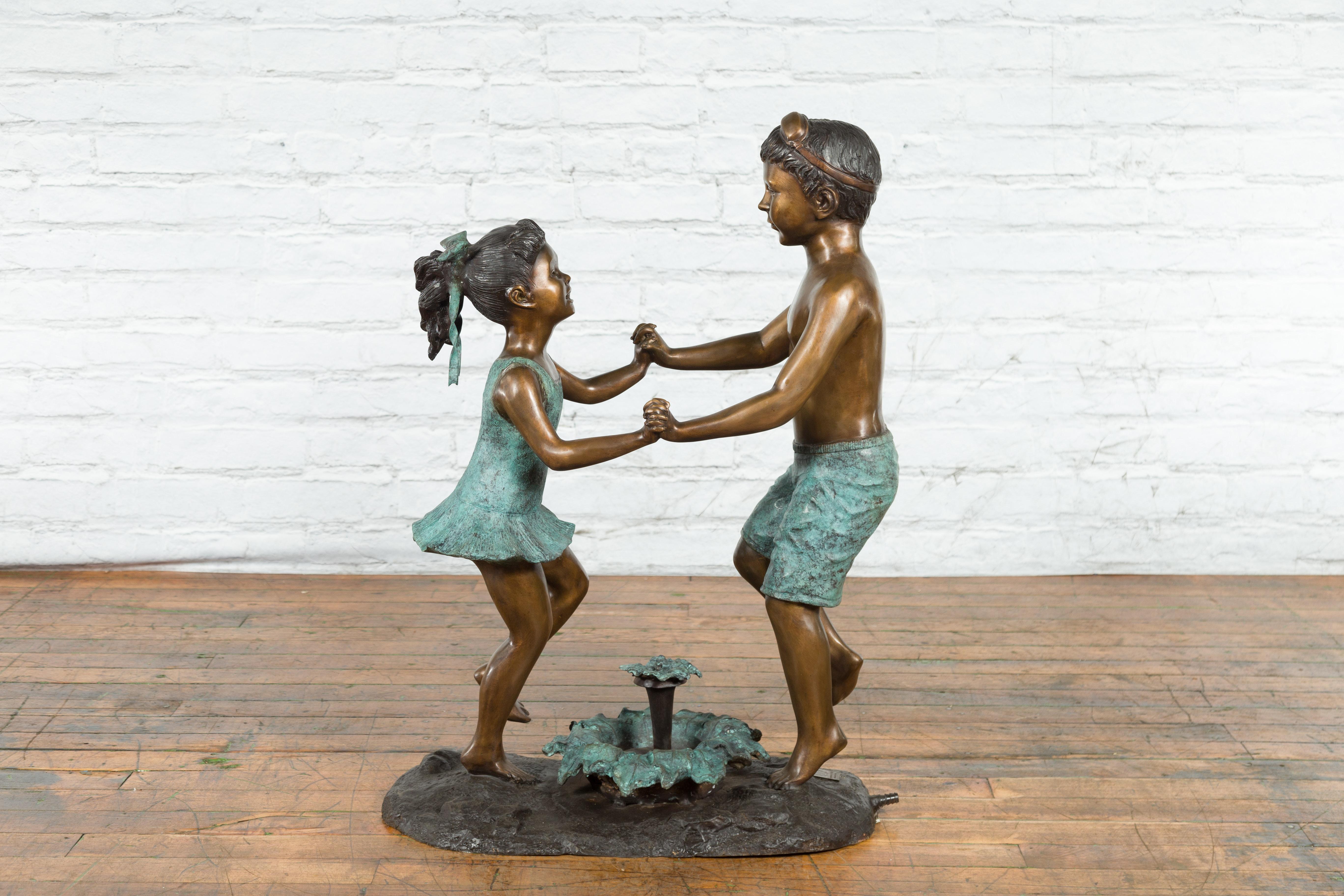 A contemporary lost wax cast bronze sculpted group depicting dancing siblings with hand-applied bronze and verdigris patina, tubed as a fountain. This is a current production, and the lead time would be 4 to 5 months. Created with the traditional