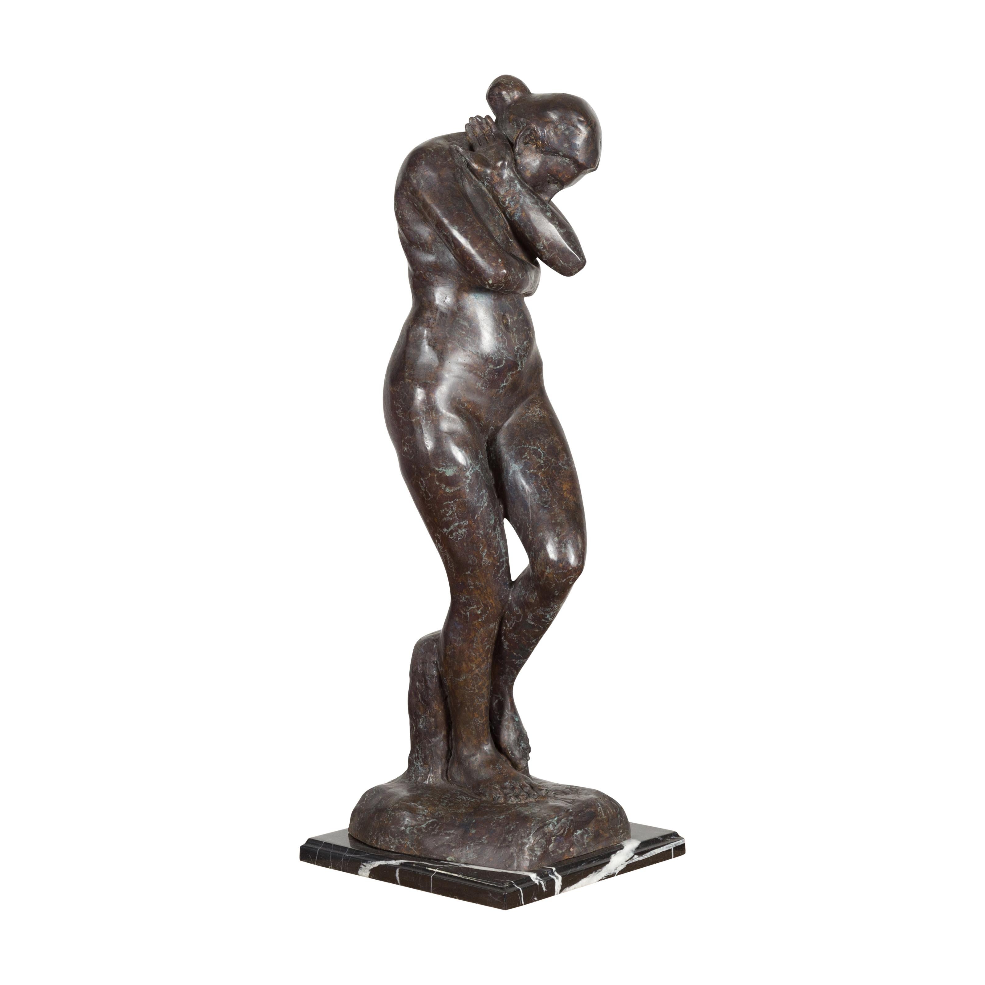 A lost wax cast bronze sculpture, inspired by Auguste Rodin's Eve in dark patina on black and white veined marble base. This item is available now and this is also a current production. Created with the traditional technique of the lost-wax (à la