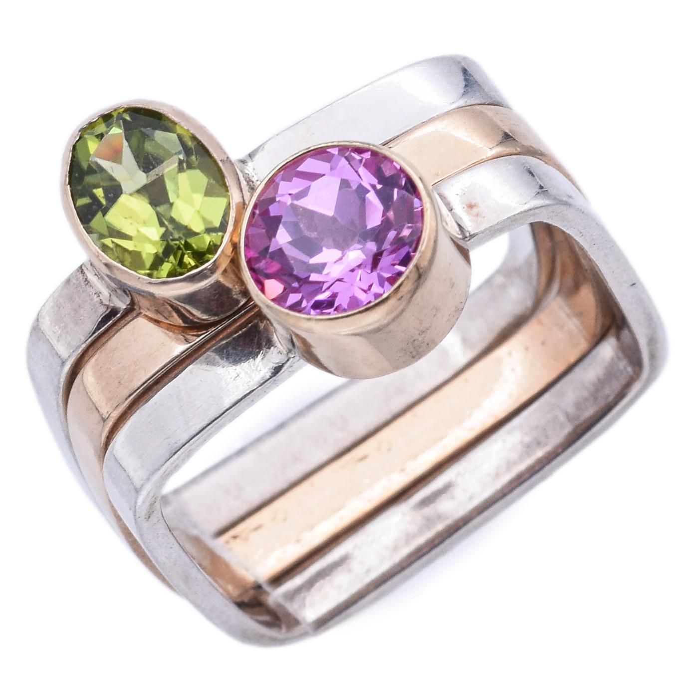 Una fusione di geometria, colore e brillantezza. Questi straordinari anelli presentano un peridoto verde e uno zaffiro rosa, entrambi con taglio rotondo e incastonati in un design elegante. Le pietre sono montate con eleganza in oro 14k su fasce