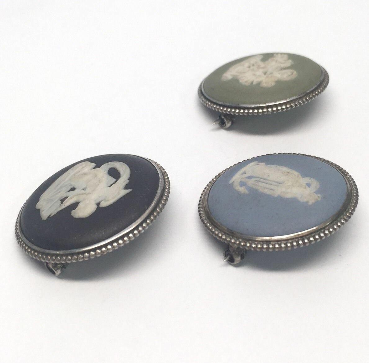 Lot of 3 Wedgwood cameo jasperware pins. Designs include black and white cherub/angel, blue and white woman, and green and white horse carriage and rider on cloud.

Marking:

Blue- WEDGWOOD MADE IN ENGLAND, 69W, SILVER FAW.

Green- WEDGWOOD MADE IN