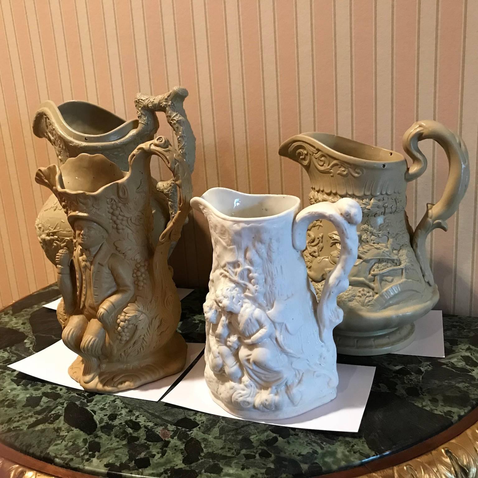 Lot of four ceramic relief pitchers and jugs, all beautifully decorated with scenes and vines. Dimensions (height x width)- First: 7