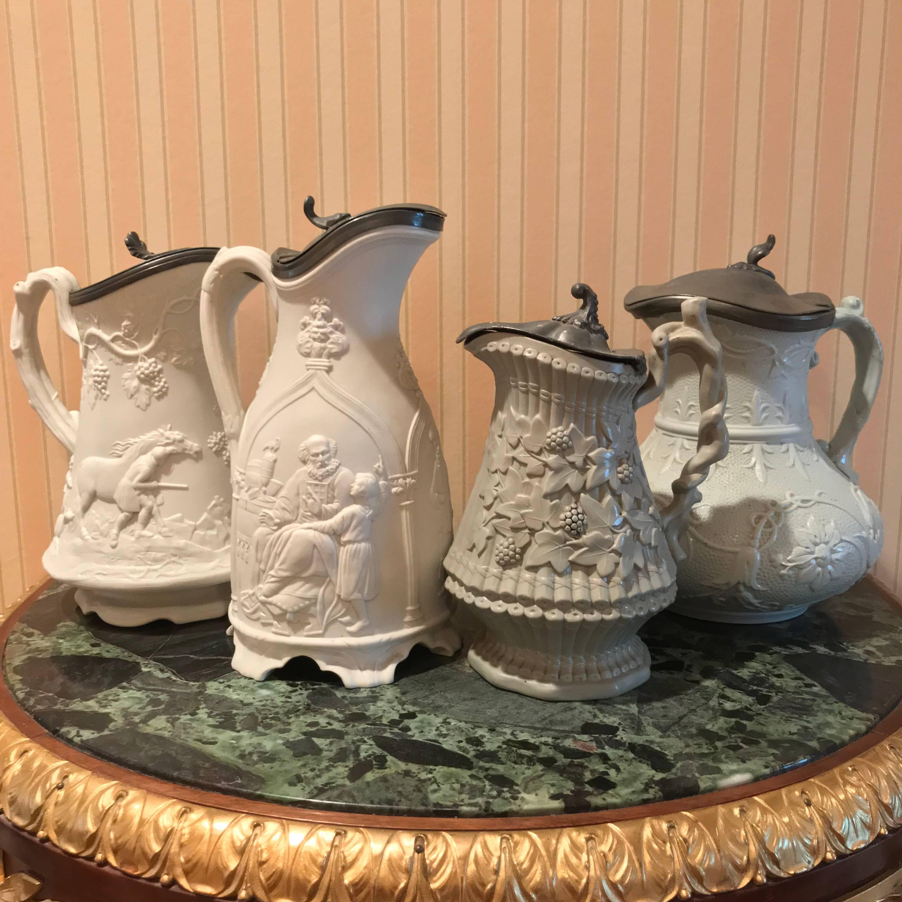 Lot of four Pewter flip top relief pitchers, all decorated with hunting/floral scenes. Measures: 1) 8
