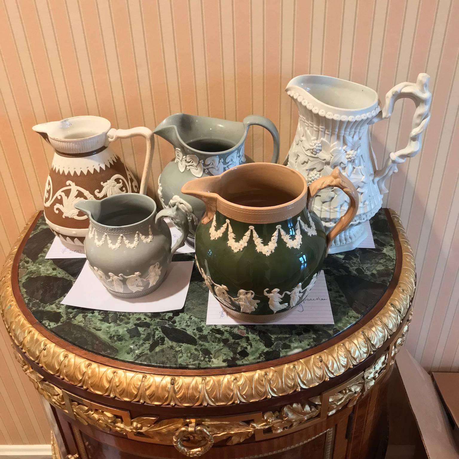 Lot of five relief pitchers and jugs with decorated scenes; several by Cobridge and Copelands. All are in excellent condition and marked on bottom. Dimensions (Height x Width) - First: 7