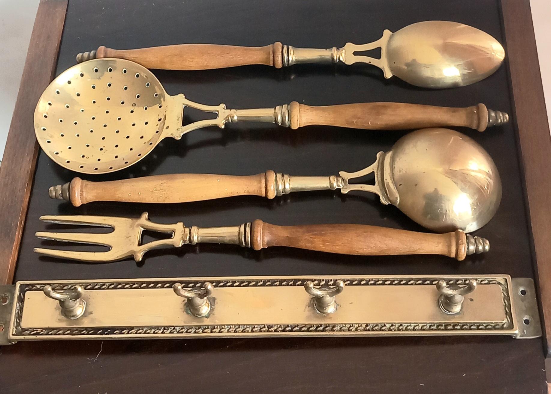 Old kitchen tools or utensils made of wood and brass hanging from a hanging bar. Old kitchen appliance  Midcentury  or Early

Saucepan fork palette and serving pot

This set of brass utensils is ideal to decorate a kitchen of any style, because its