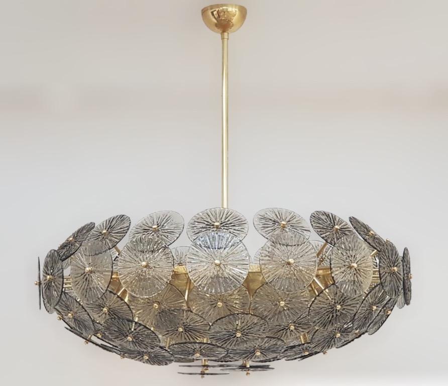 Lampadario italiano oversize con dischi in vetro di Murano fumé stratificati e testurizzati montati su una struttura in ottone massiccio con finitura laccata lucida, disegnato da Fabio Bergomi per Fabio Ltd / Made in Italy
16 luci / tipo E12 o E14 /