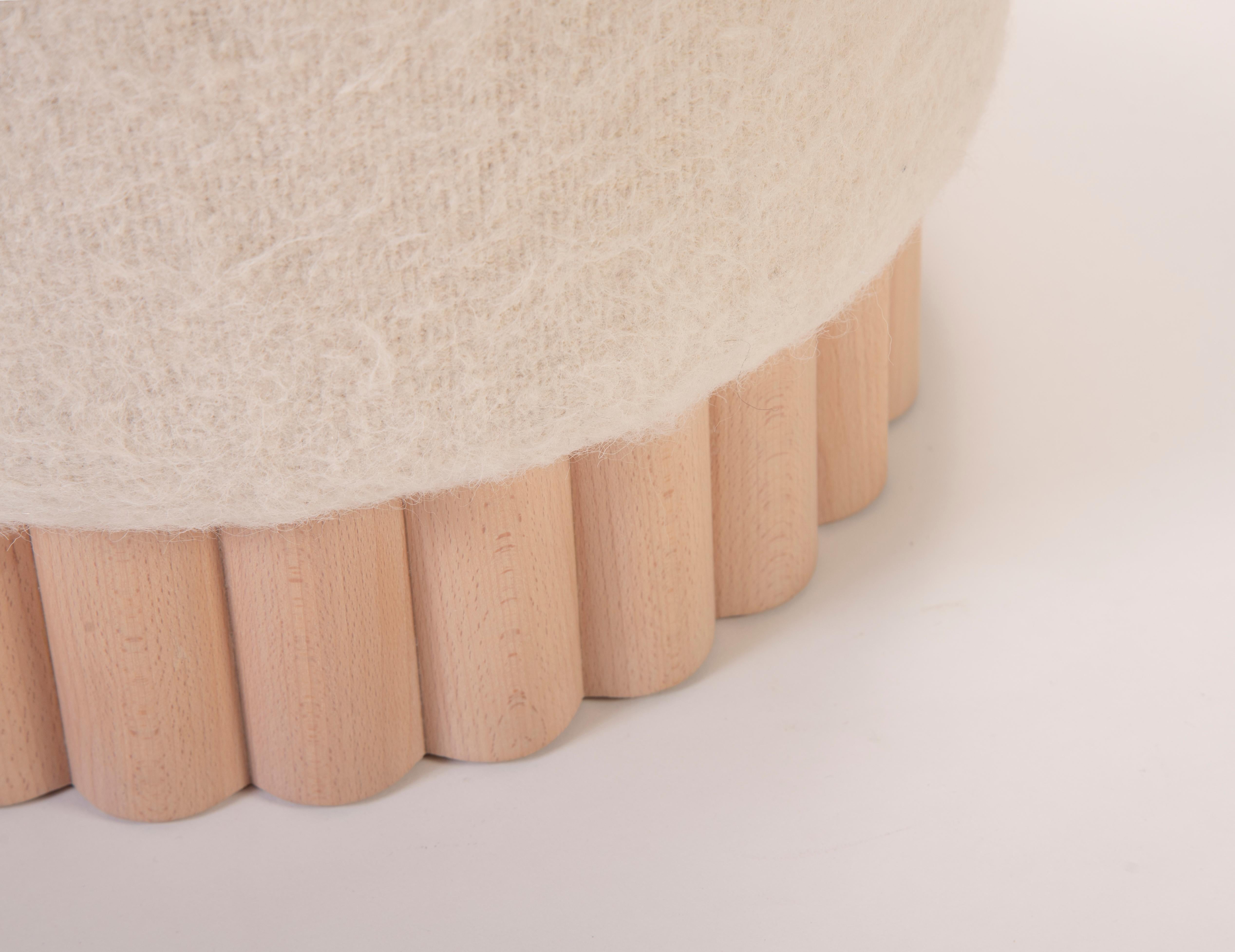 Upholstered with a choice of different types of fabrics such as Lambswool Cloth, Linen or the softness of Leather, our Loto pouf bares only the slightest peek of its wooden rod base, drawing attention to the contrast of the two different