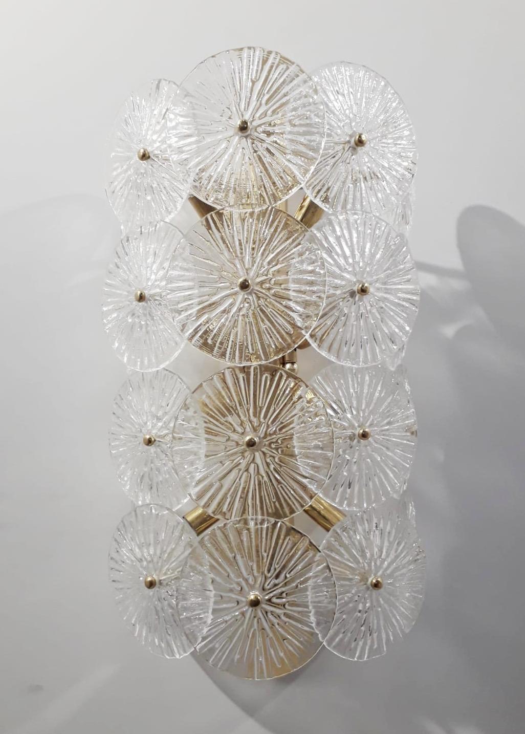 Impresionante aplique italiano sobredimensionado con discos de cristal de Murano de textura transparente montados sobre un marco de latón macizo en acabado lacado pulido, diseñado por Fabio Bergomi para Fabio Ltd, fabricado en Italia.
8 luces / tipo
