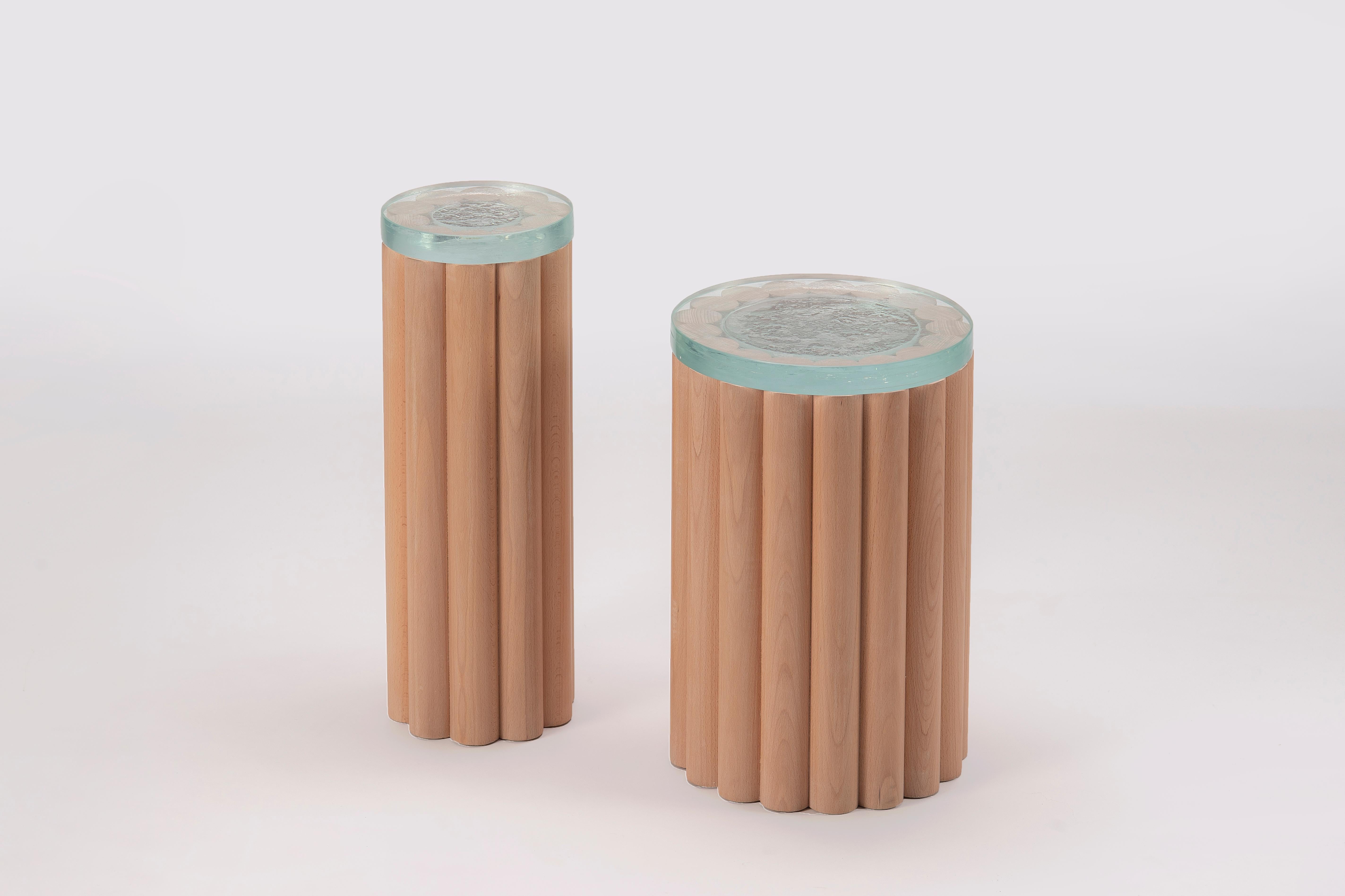 Inspired in the exercise of experimenting with a number of turned rods of wood. Loto side-tables are a simple yet stylish statement, featuring two cylindrical bodies in different diameters and heights and Tlaquepaque molten glass fused tops