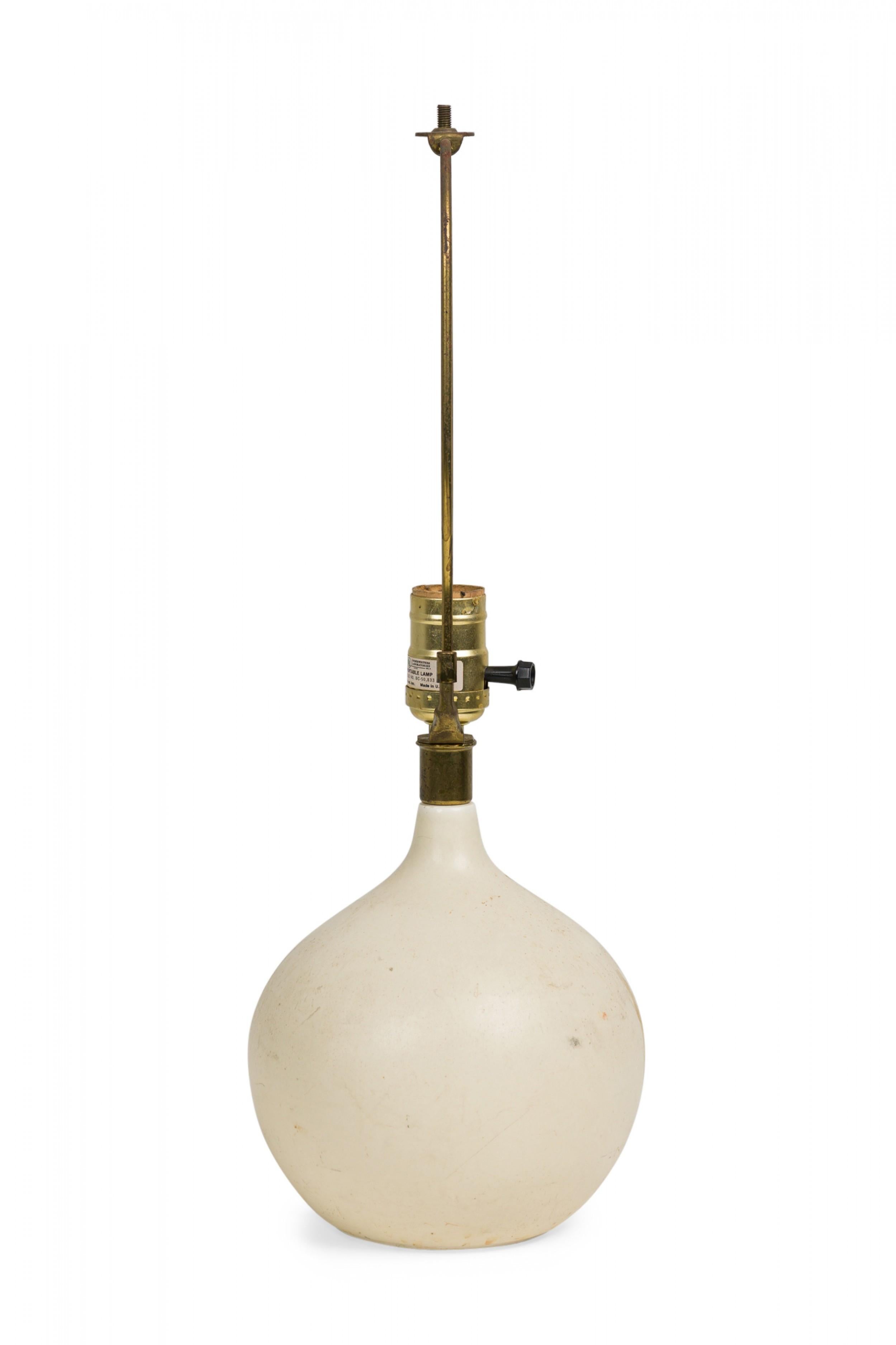Midcentury (1960s) Danish ceramic bone stoneware table lamp in orb form with pinched neck featuring an extended brass functioning light switch socket plus harp, the body fired in a matte white glaze. (LOTTE AND GUNNAR BOSTLUND)