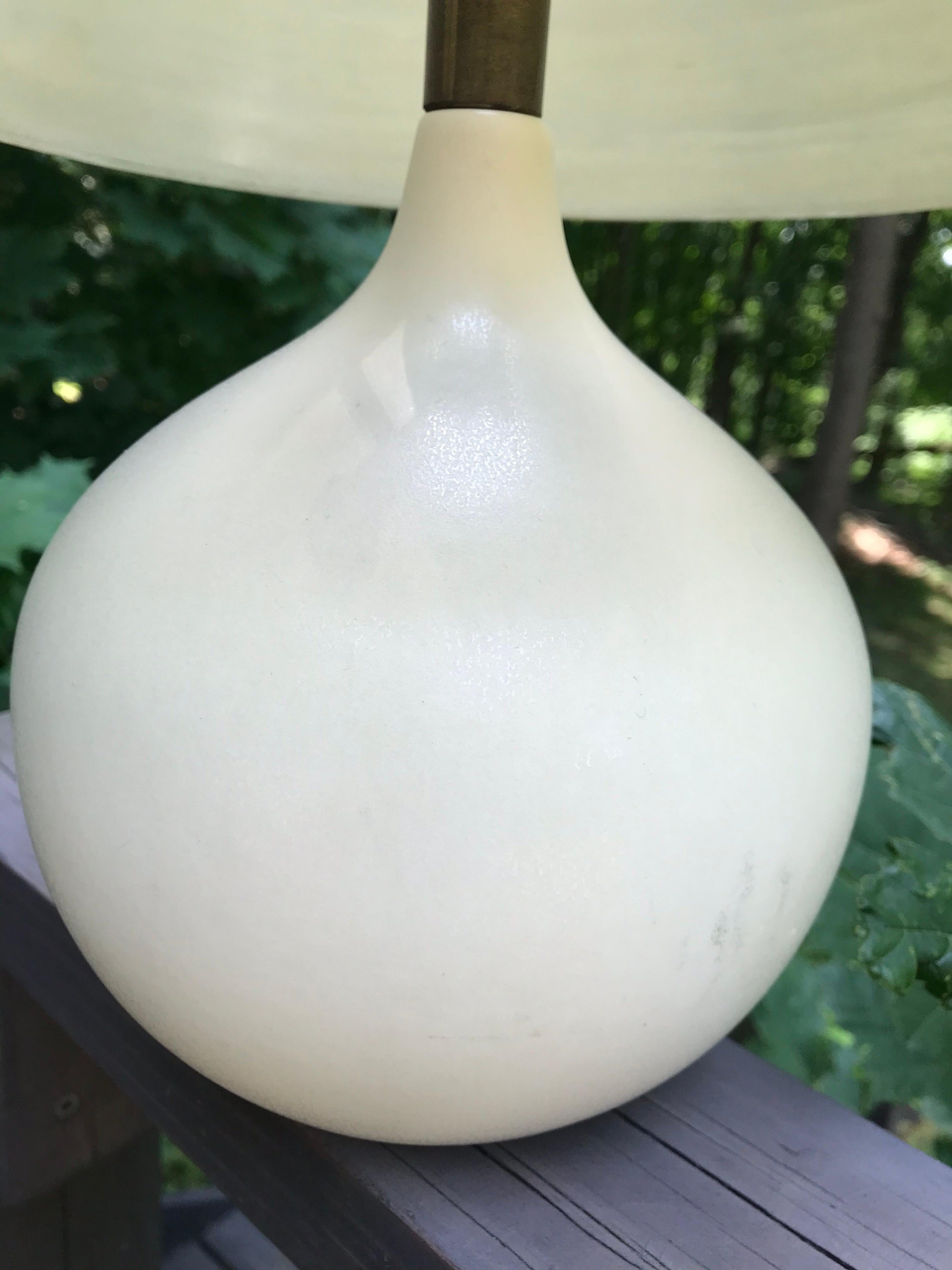 Eggshell white ceramic table lamp with the original grass cloth fiberglass shade. Signed with paper label, Bostlund Industries, circa 1960. Original wiring in good working condition.