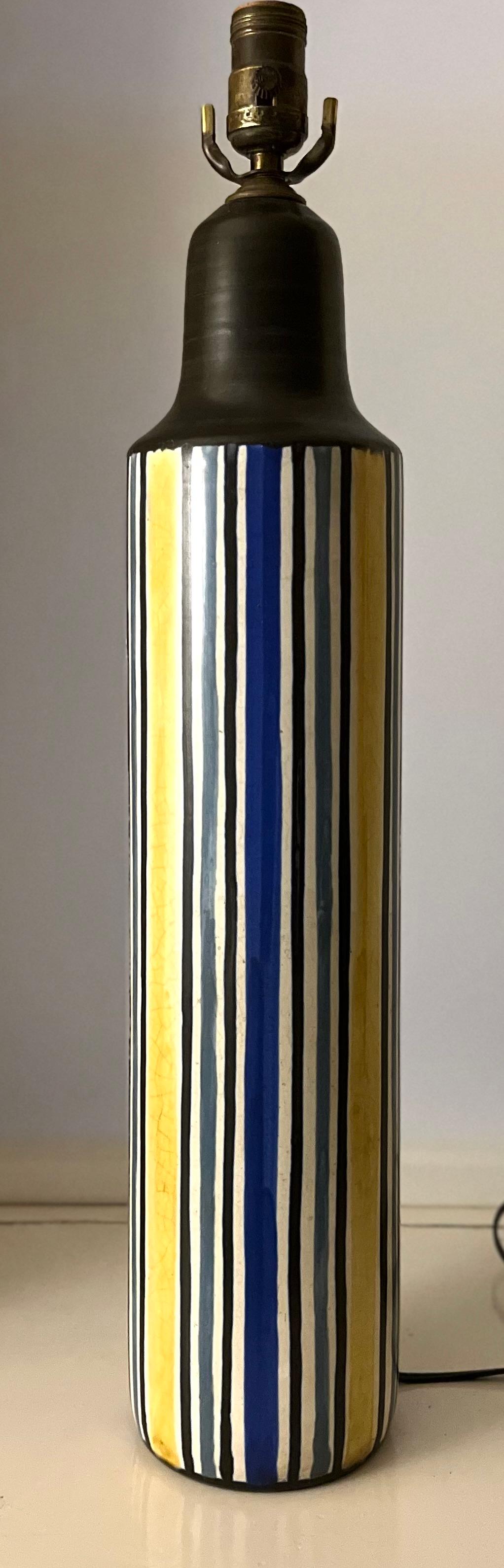 A rare mid-20th century table lamp in ceramic by Lotte and Gunnar Bostlund, recently rewired, model #302. White background with yellow, blue and grey stripes. Signed “Lotte” in the glaze. 

The History of Lotte Lamps and the Bostlund Family
The