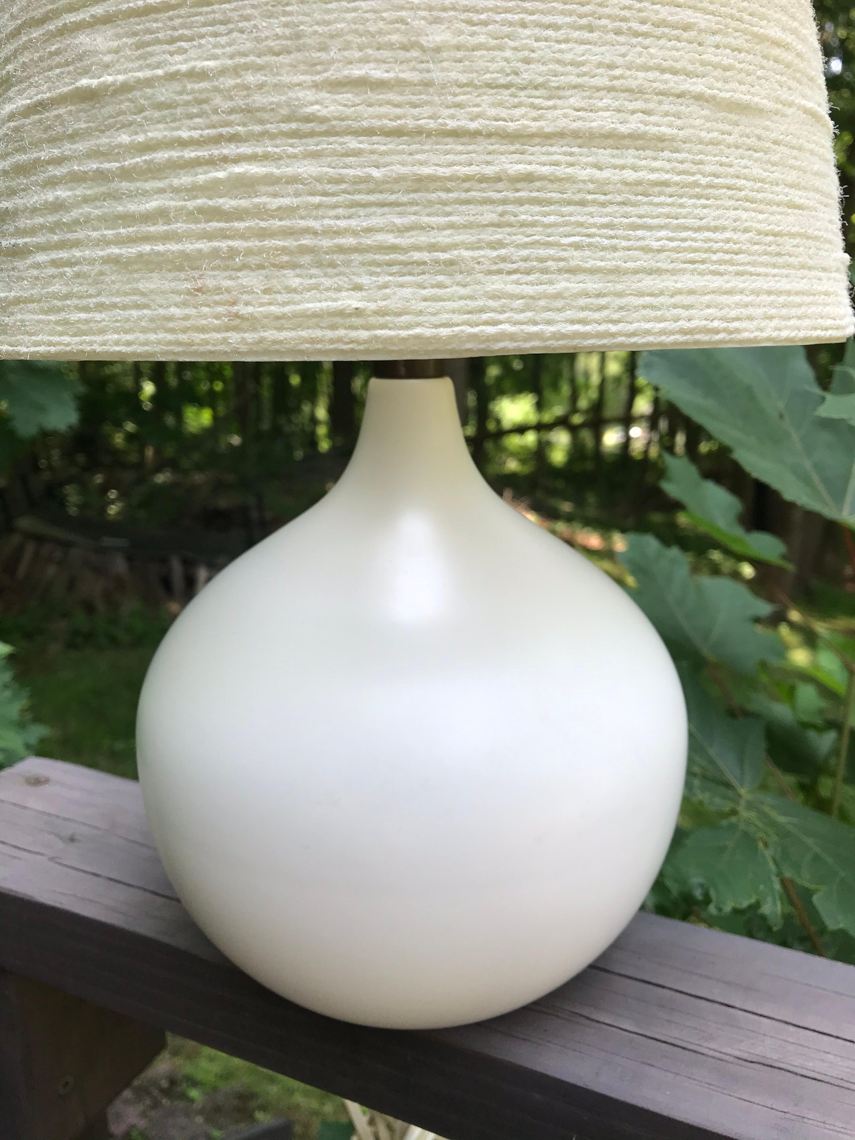 Pearl white ceramic table lamp with the original grass cloth fiberglass shade. Signed with paper label, Bostlund Industries, circa 1960. Original wiring in good working condition.