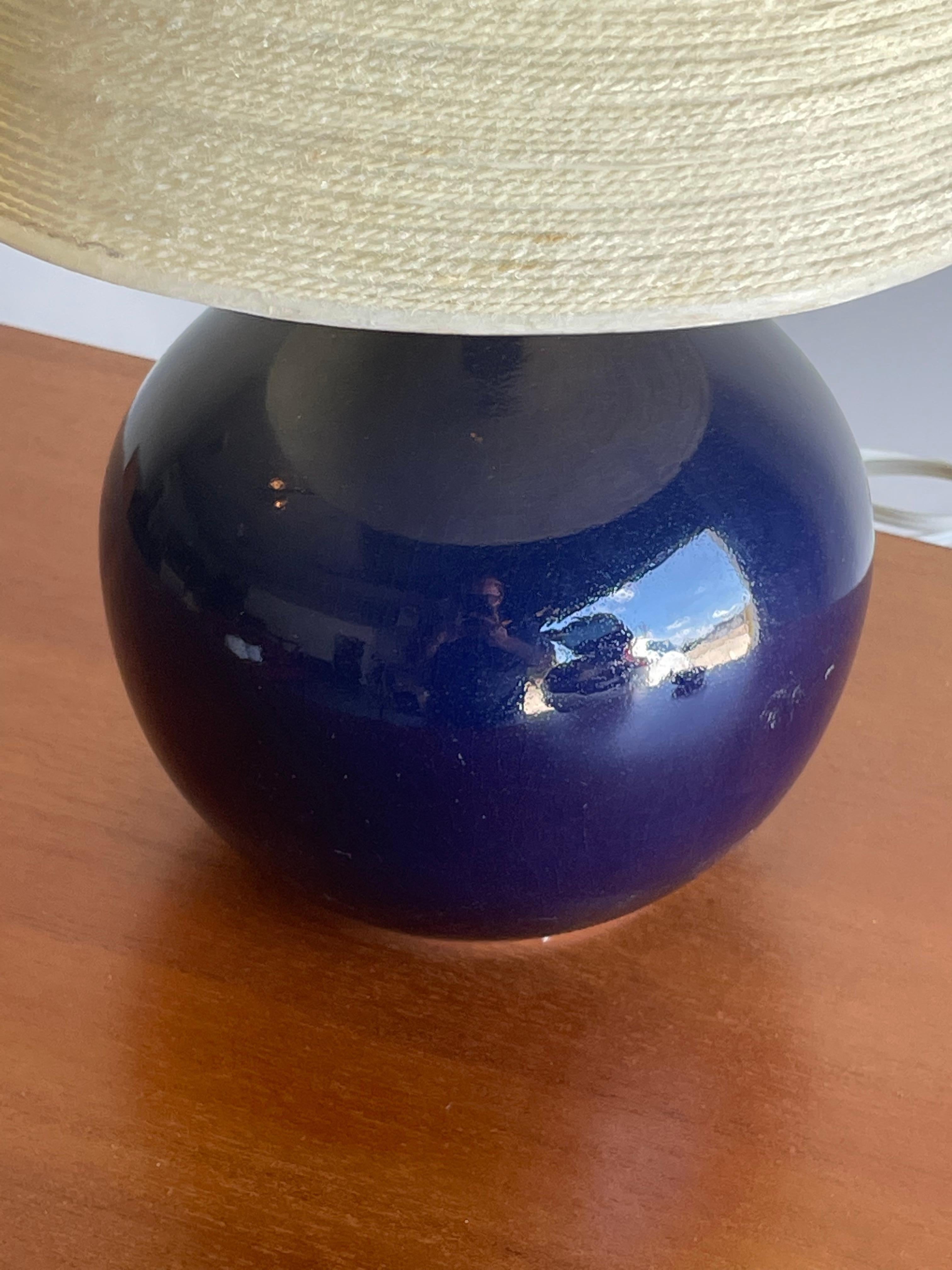 Lotte and Gunnar Bostlund table lamp in royal blue glossy ceramic glaze. Iconic color by duo. While from Denmark, the two operated out of Canada and the US.

Measures: Overall 
16.5” tall

Ceramic portion 
7.5” tall
6.5” wide

Shade
6.25”