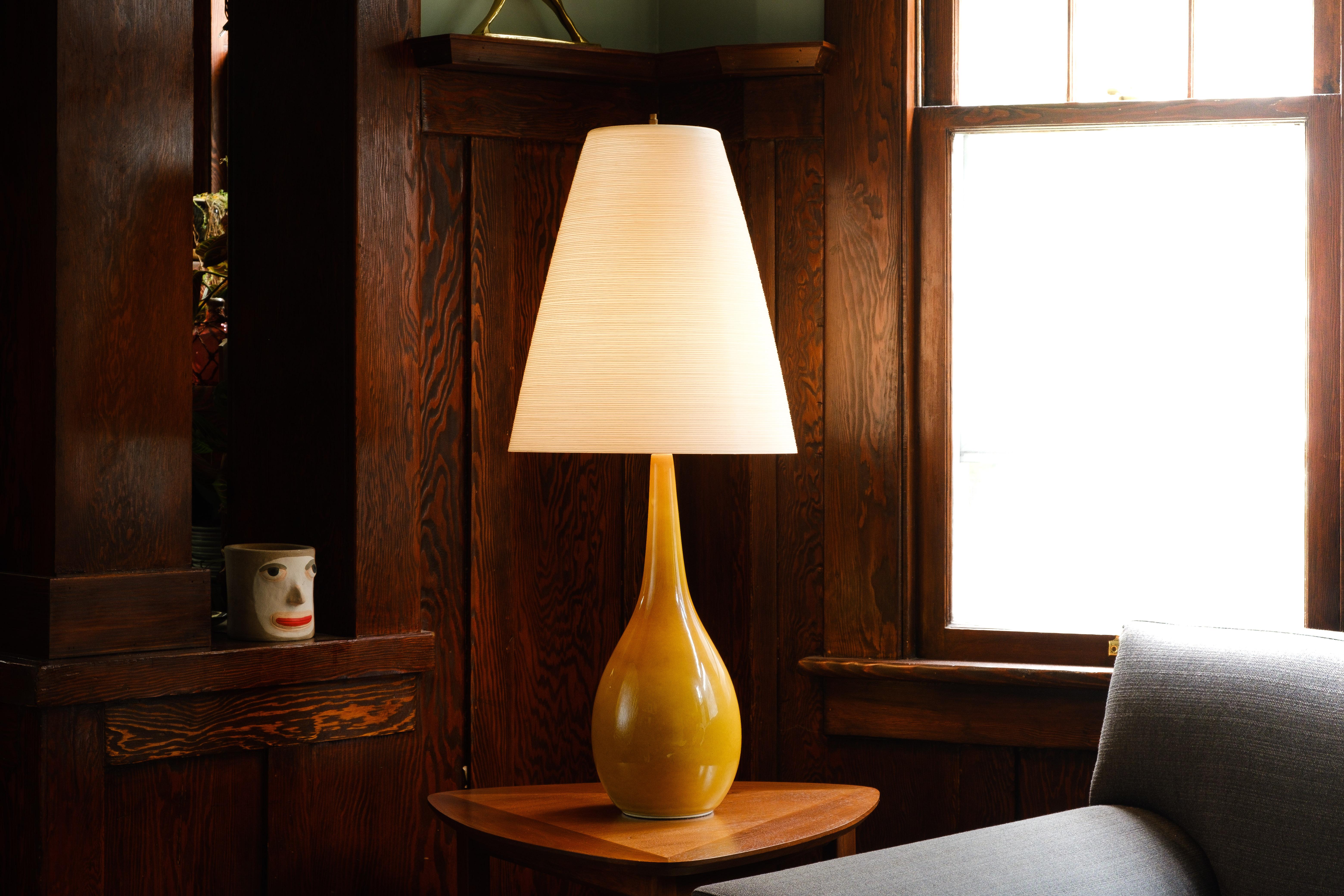What is it?
—
A signed Lotte Bostlund lamp from the 1970s. Bright yellow glaze on a very tall ceramic body. Comes with the original cord wrapped fiberglass shade. 

Lotte Lamps were developed by the husband and wife team of Lotte and Gunnar