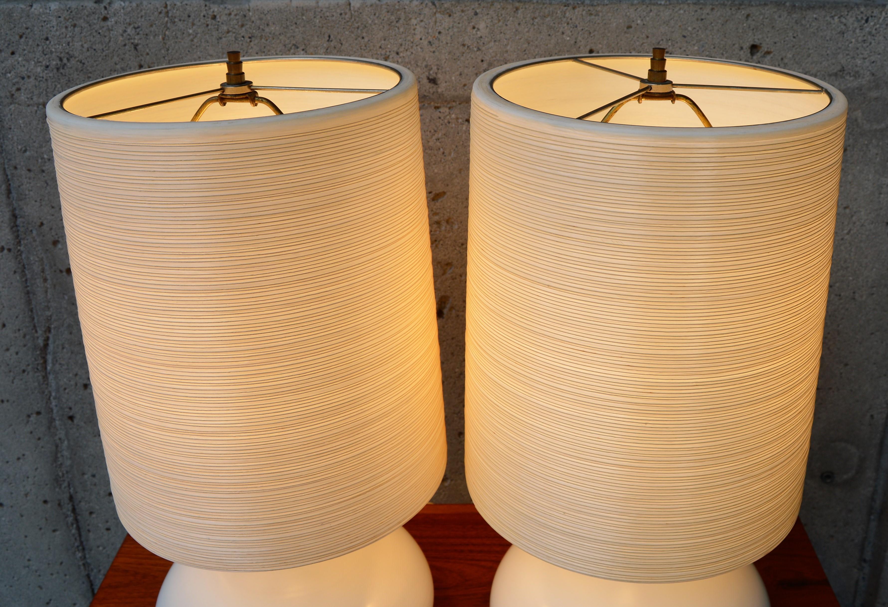 This lovely sculptural pair of ceramic lamps were designed and made by Lotte and Gunnar Bostlund in the 1960s. In an elegant off white that is timeless, and paired with their original Bostlund fiberglass conical shades with a hand-applied fiber