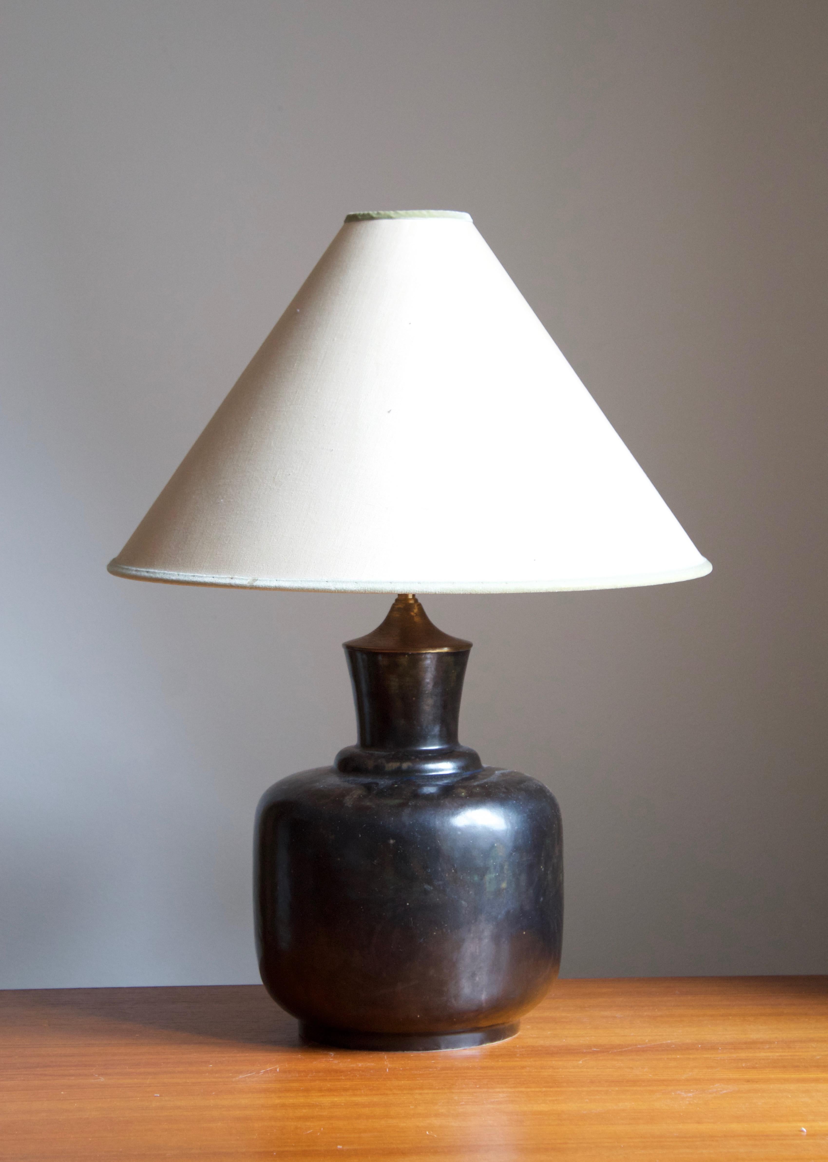 A sizable table lamp, designed by Lottie Lindahl. Produced by Bing & Grøndahl, Denmark, 1940s. Features an exceptional glaze, typical of Bing & Grøndahl production.

Stated dimensions exclude illustrated lampshade. Height includes harp