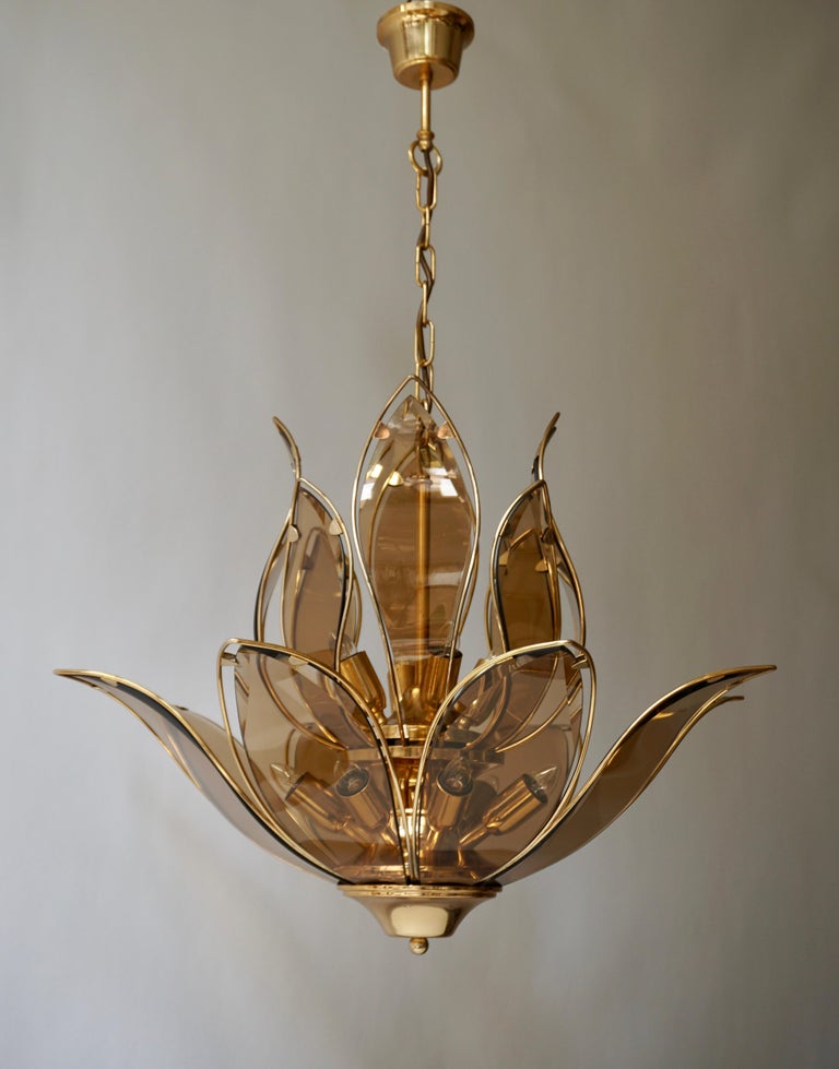 An outstanding and highly elegant brass and Murano glass chandelier in lotus flower shape of very good quality. This chandelier dates from the 1970s and is Italian by origin. 
The light requires twelve single E14 screw fit lightbulbs (60Watt max.)
