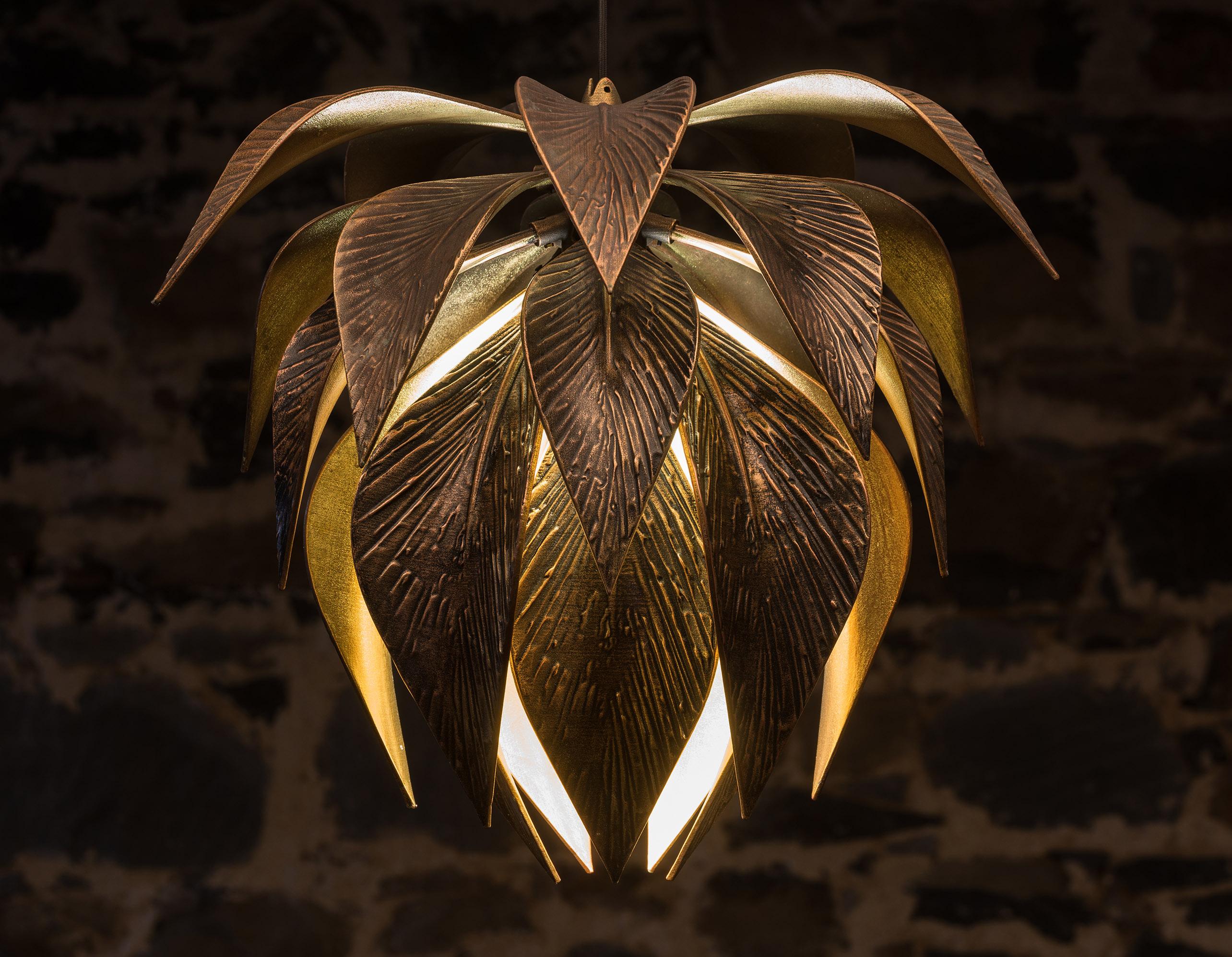 La lampe suspendue Lotus respire le luxe et la sophistication, offrant un aperçu spectaculaire du dessus et du dessous de chaque feuille. Chaque angle de la lumière offre une vue unique et fascinante de ses feuilles métalliques. Cette suspension