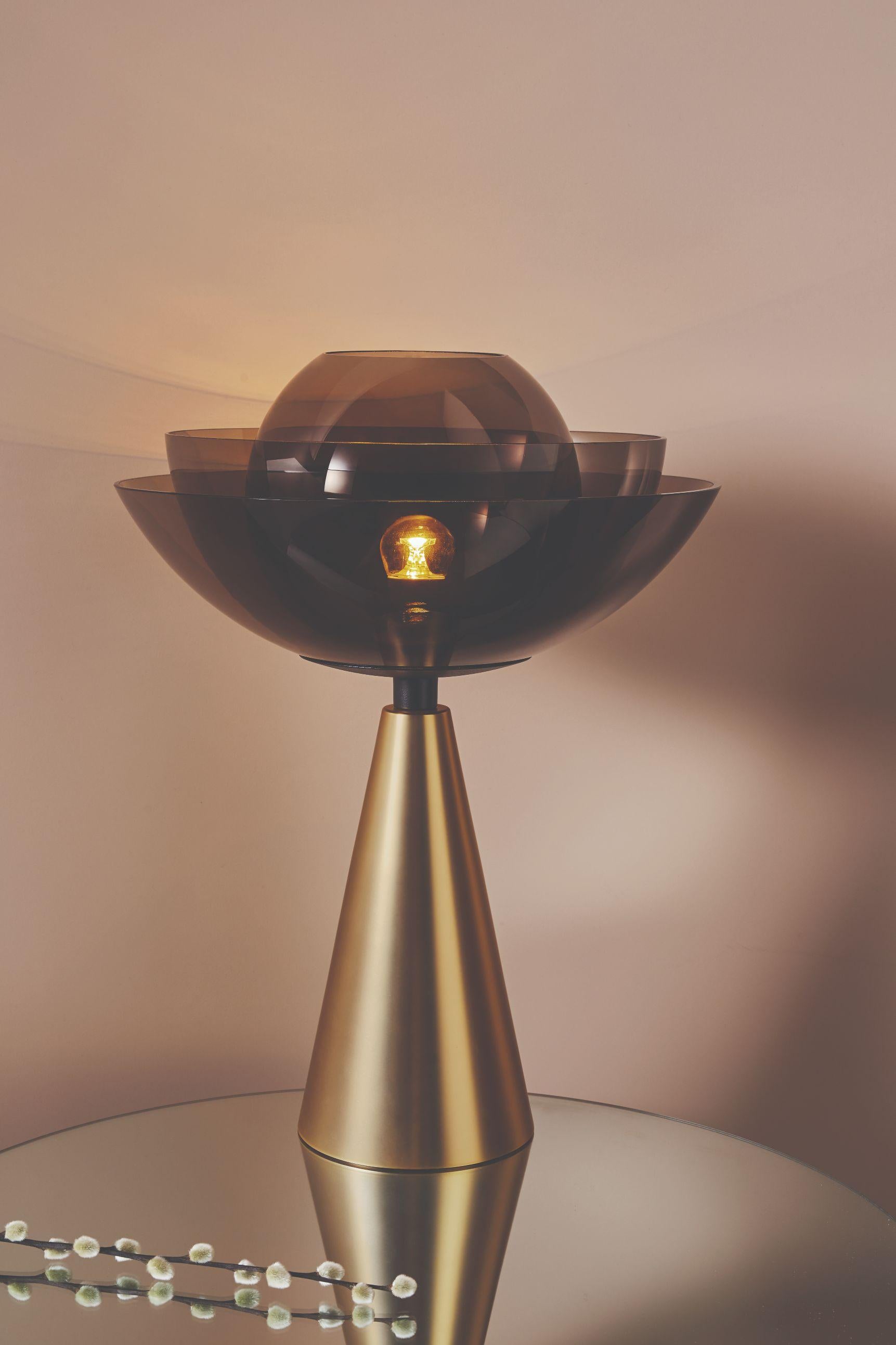 Lotus table lamp by Mason Editions.
Dimensions: 36 x 36 x 48 cm.
Materials: Brown glass and metal.

With its fascinating shape and heady scent, for many Asian cultures, the lotus flower symbolizes elegance,
beauty, perfection, purity, and