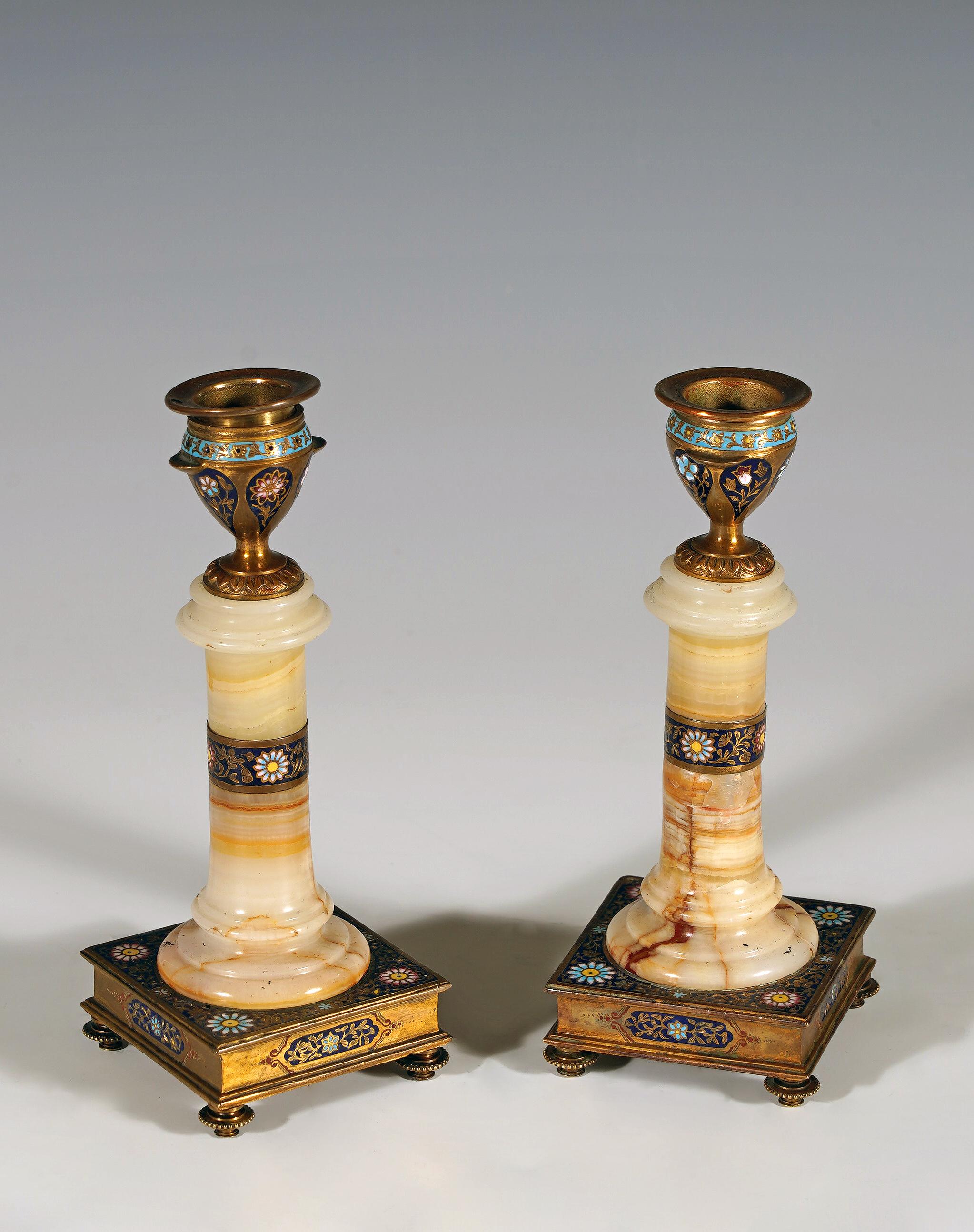 Affascinante coppia di candelabri orientalisti in onice algerino a coste e bronzo dorato, con fusto a forma di colonna modellata. Il binet, l'anello centrale e la base quadrata sono decorati con smalti cloisonné con motivi floreali. Il tutto poggia