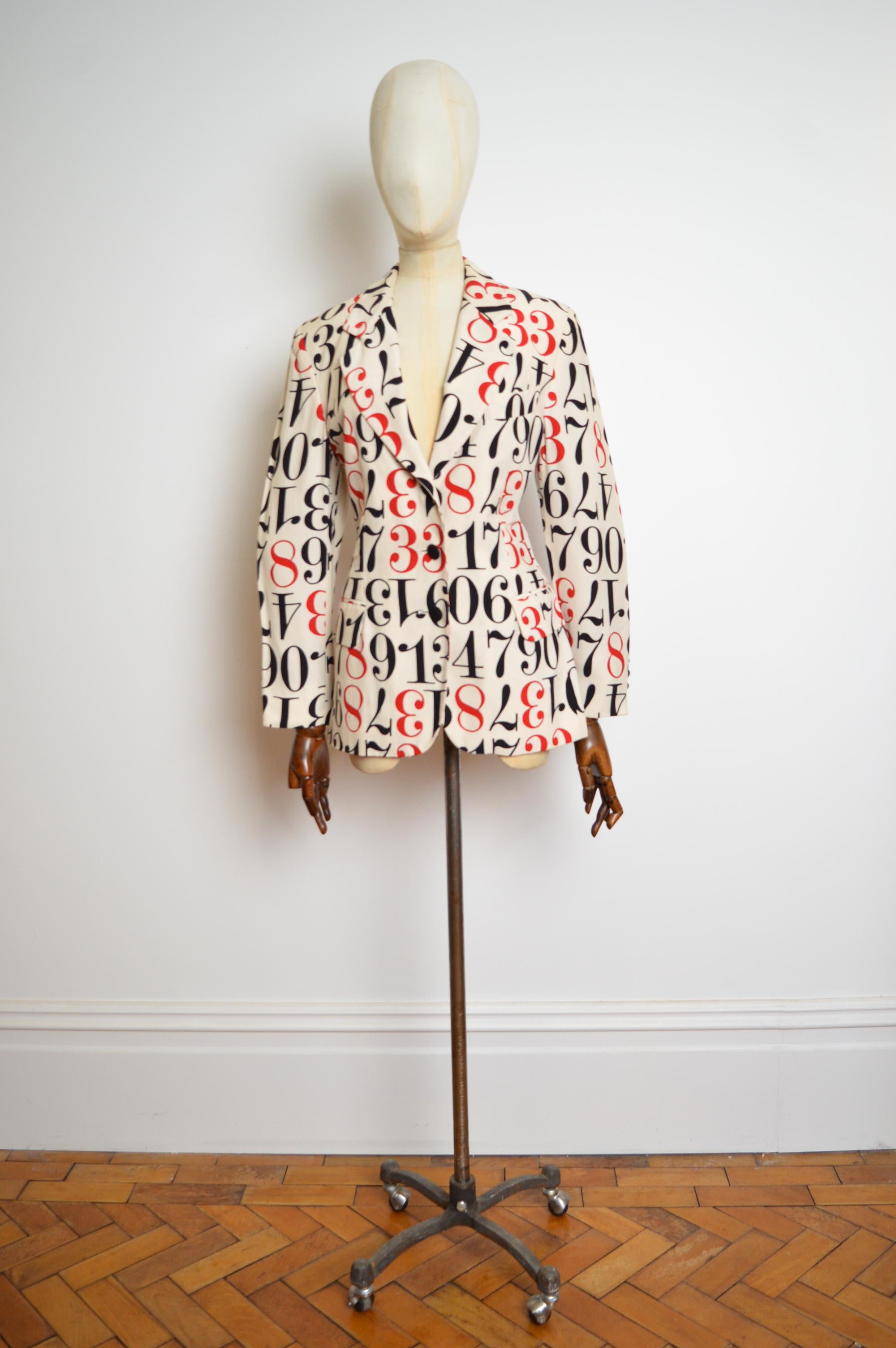 1990’s Moschino Cheap & Chic Blazer designed by Franco Moschino. 
MADE IN ITALY.
Crafted from an off-white rayon fabric with repeat numeral print in Black and red through out aswell as the typical Moschino Cheap and chic pearlescent cream jacquard