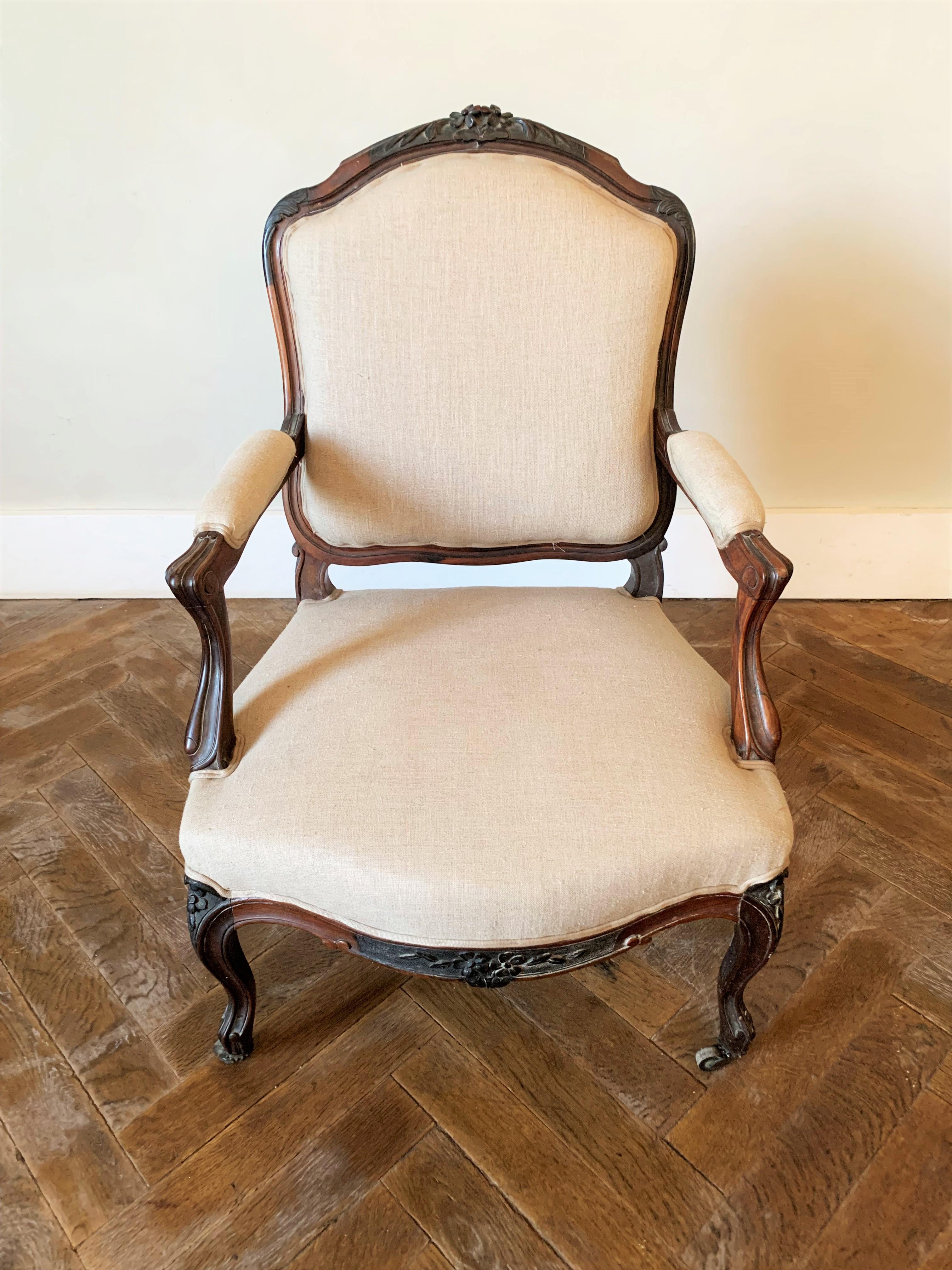 Magnifique fauteuil à la Reine de style Louis XV, richement sculpté de feuillages sur la traverse supérieure du dossier et de motifs floraux sur les pieds galbés. La finesse des sculptures présente des proportions élégantes qui font le charme de ce