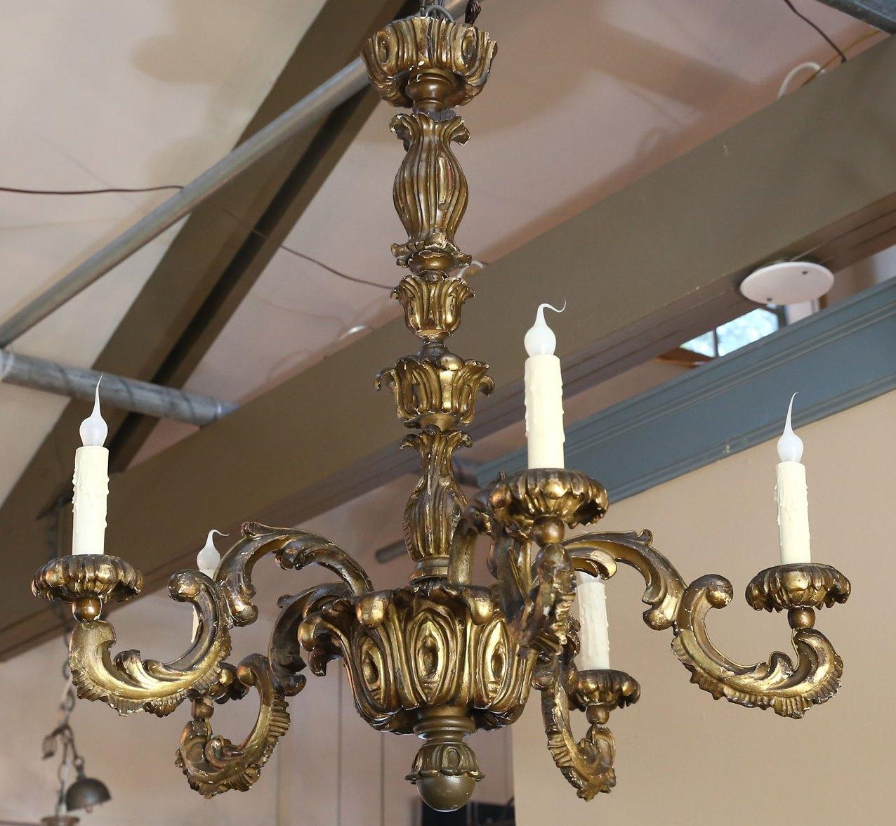 This antique carved wood chandelier has nice color and nice gilt on wood finish. It has been newly wired for the United States. There is previous repair on an arm that has been professionally done. The proportions are lovely and it has an authentic