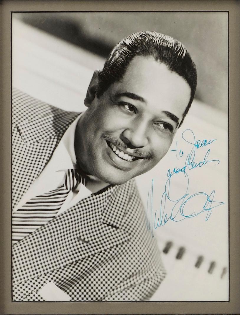 Presented is a stunning collage featuring jazz music legends Louis Armstrong and Duke Ellington, including photographs, signatures, and a “Roulette” Radio Station Copy Record.

Duke Ellington (1899-1974) was an American composer, pianist, and