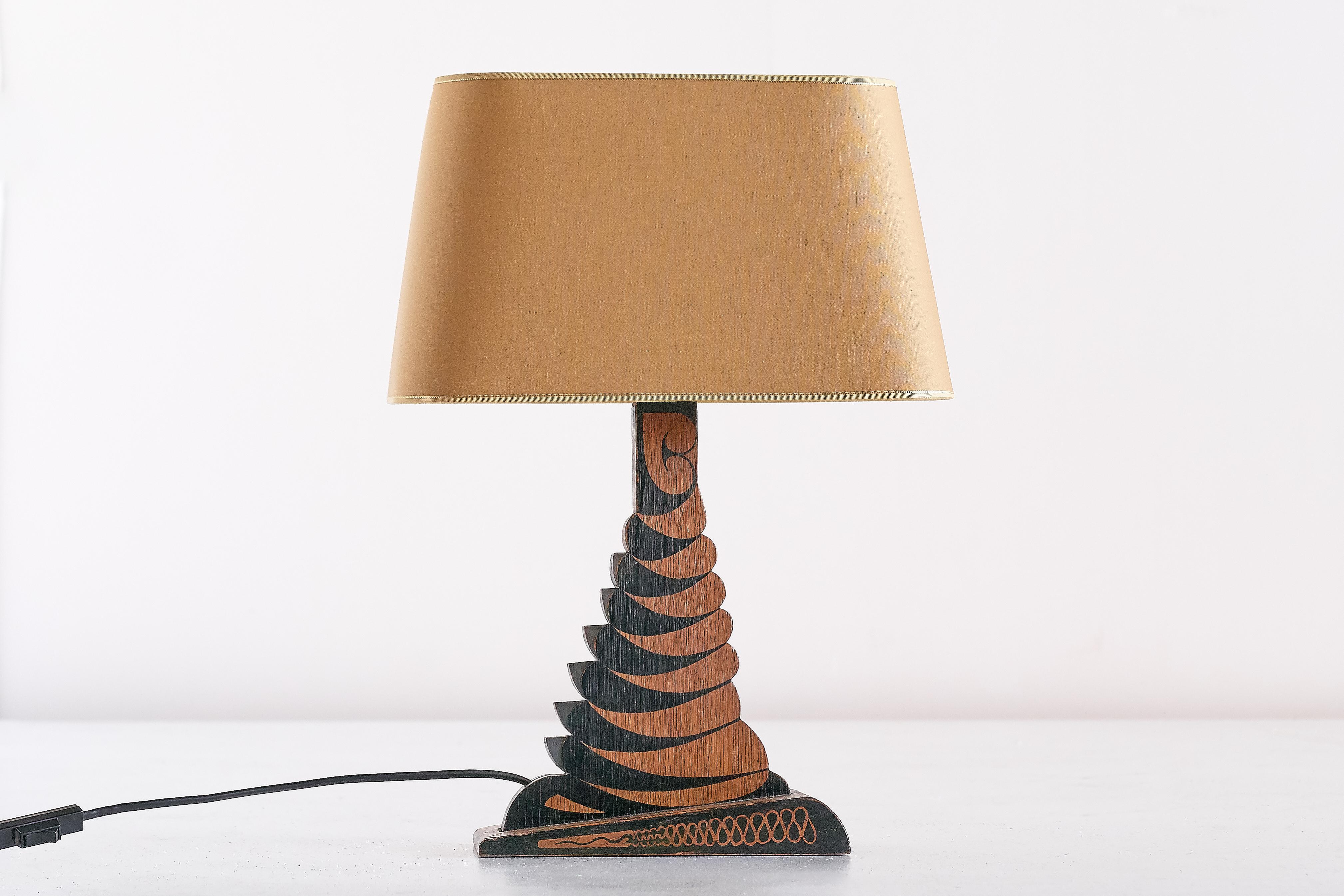 This rare table lamp was designed and made by Louis Bogtman in his workshop in Hilversum, the Netherlands, circa 1925. The lamp has an intricately detailed black batik decoration applied on a carved base in oakwood. The yellow gold shade has been