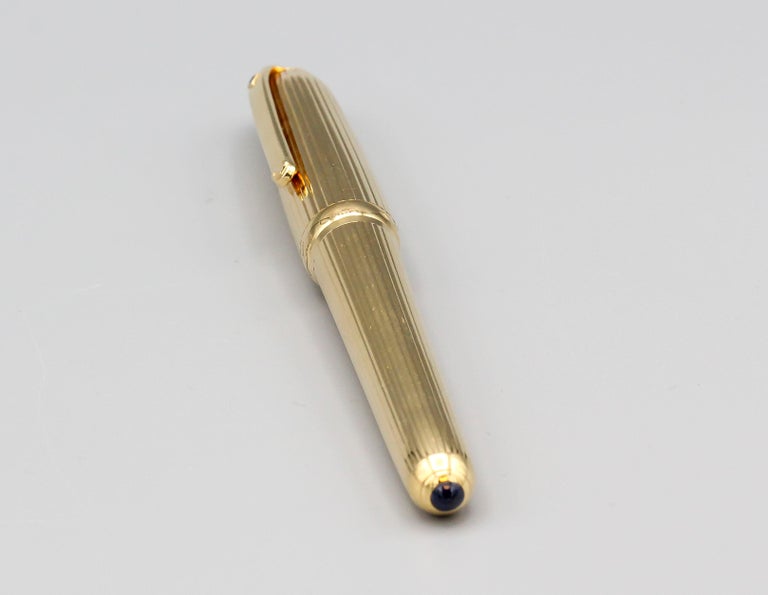 Very fine sapphire and 18K yellow gold fountain pen from the Louis Cartier collection by Cartier. It features an 18k gold nib and a ribbed stylish design. Screw cap features a diamond shaped cabochon sapphire. Beautiful workmanship and great for any