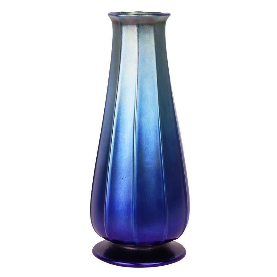 Offering this outstanding, ribbed Louis Comfort Tiffany blue Favrile iridescent art glass vase. This vase features a bulbous body with tapered neck and flared mouth design. Signed on the underneath 