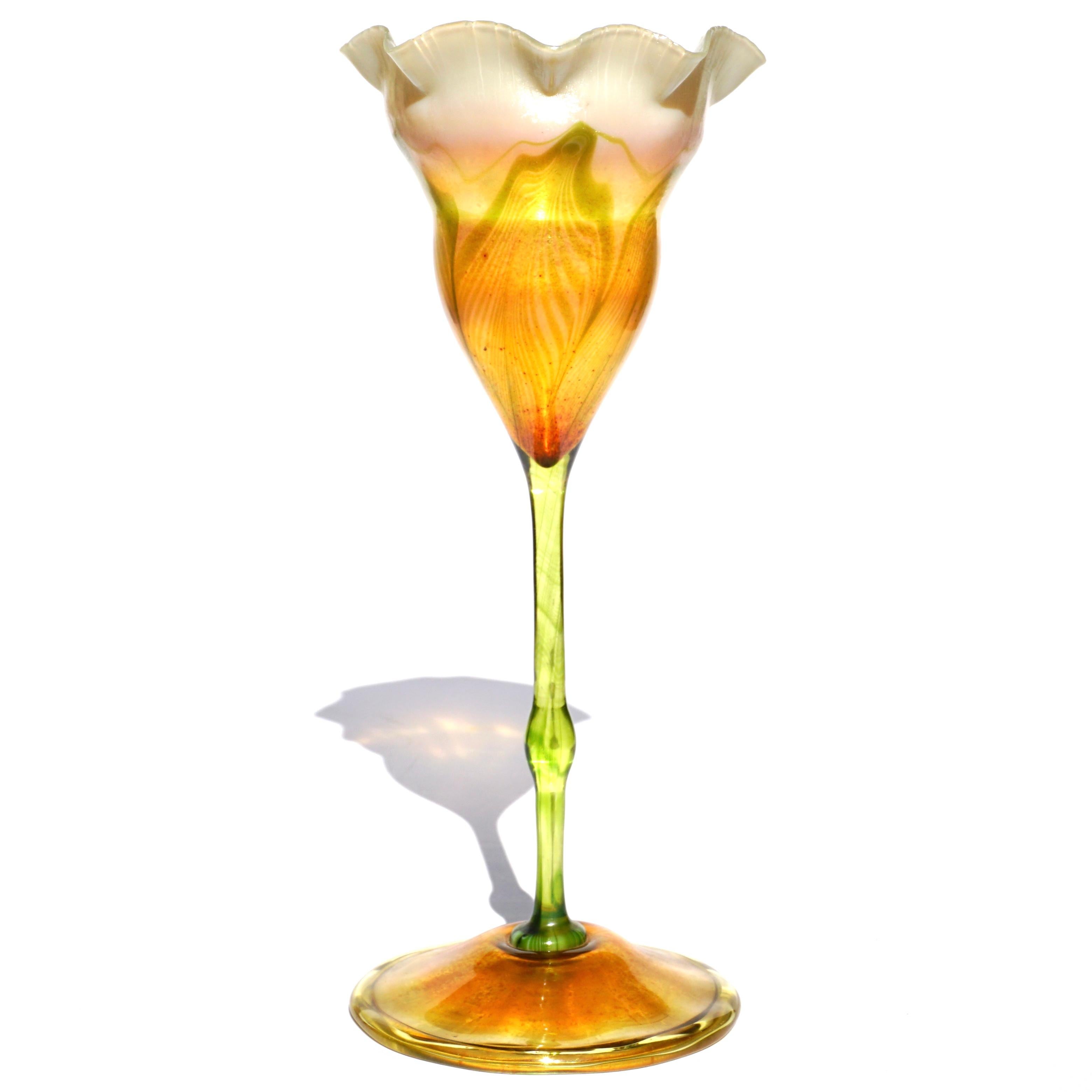 Louis Comfort Tiffany Vase aus Favrile-Glas. Um 1900 Jugendstil. Verziert mit gezogenen Federn mit zarten weißen Rüschen. Der grüne, längliche Stiel verbindet Vase und Tasse, die beide rote Flecken aufweisen, die mit Goldstaub hergestellt wurden.