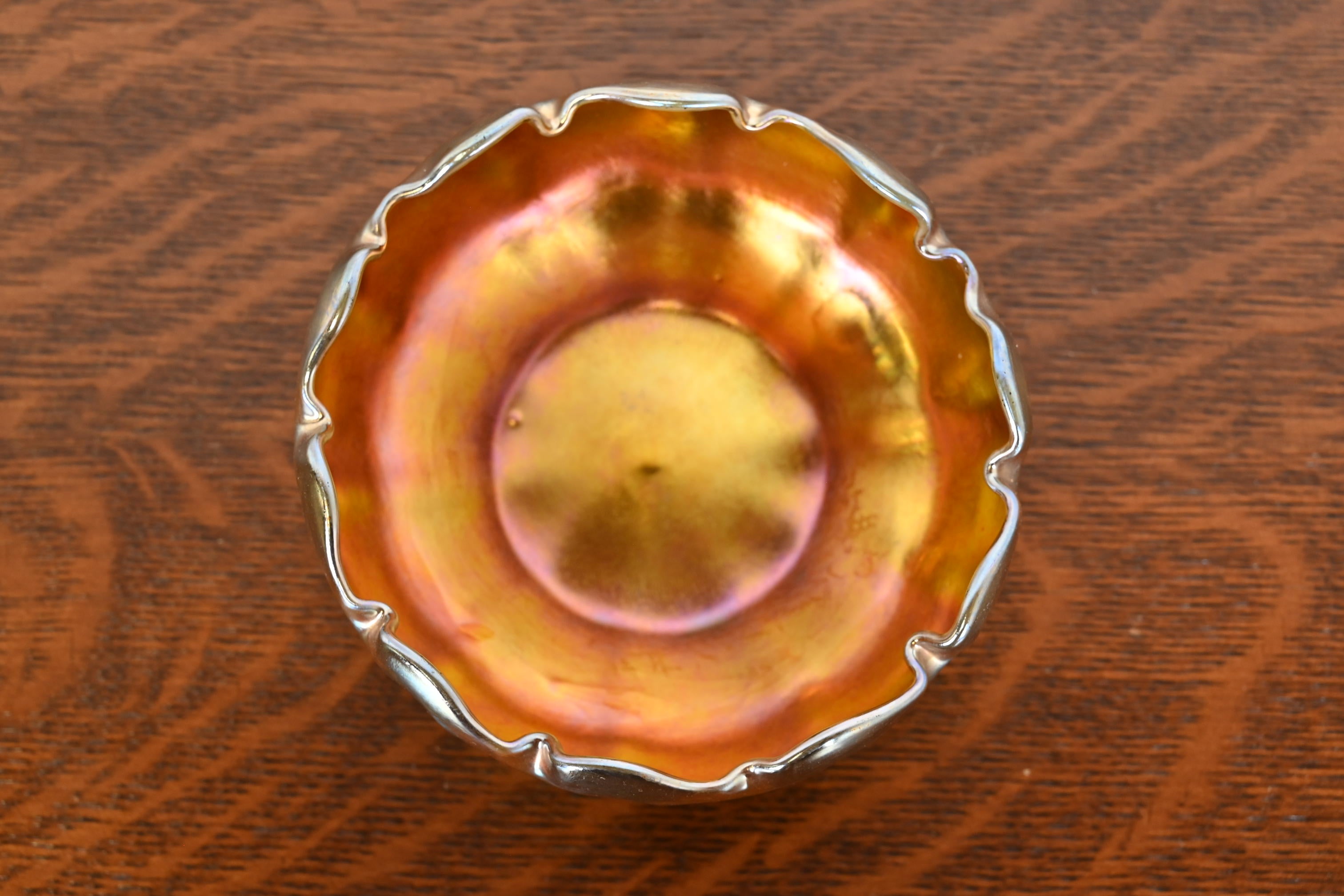 A gorgeous Arts & Crafts or Art Nouveau period Favrile iridescent art glass nut bowl with ruffled edges

By Louis Comfort Tiffany for Tiffany Studios (signed to the underside)

USA, Circa 1900

Measures: 4.88