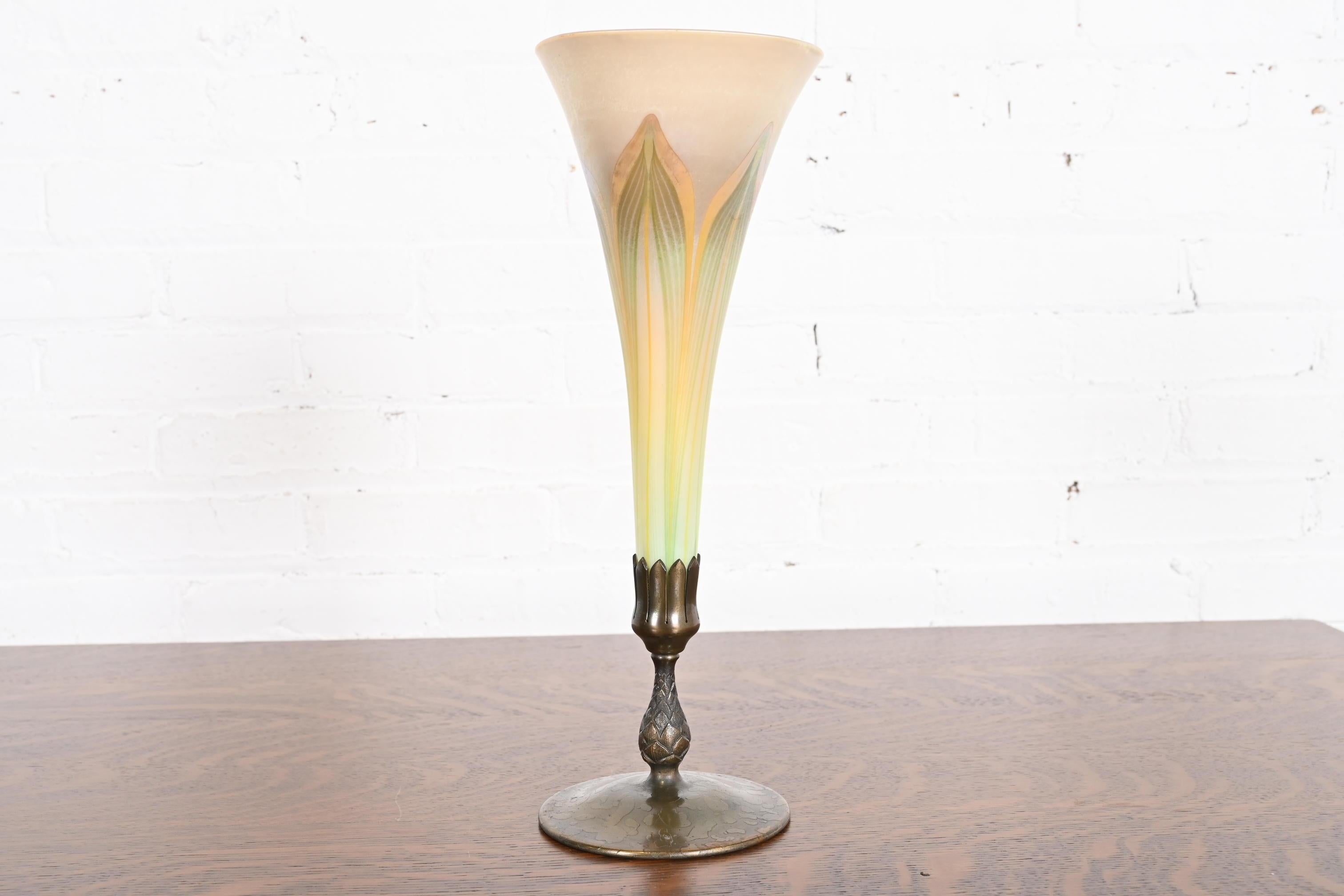 Eine wunderschöne Arts & Crafts oder Art Nouveau Periode Favrile irisierenden Kunstglas gezogen Feder hohe Trompete Vase auf Artischocke Form Bronze stehen

Von Louis Comfort Tiffany für die Tiffany Studios. Sowohl die Vase als auch der Sockel sind