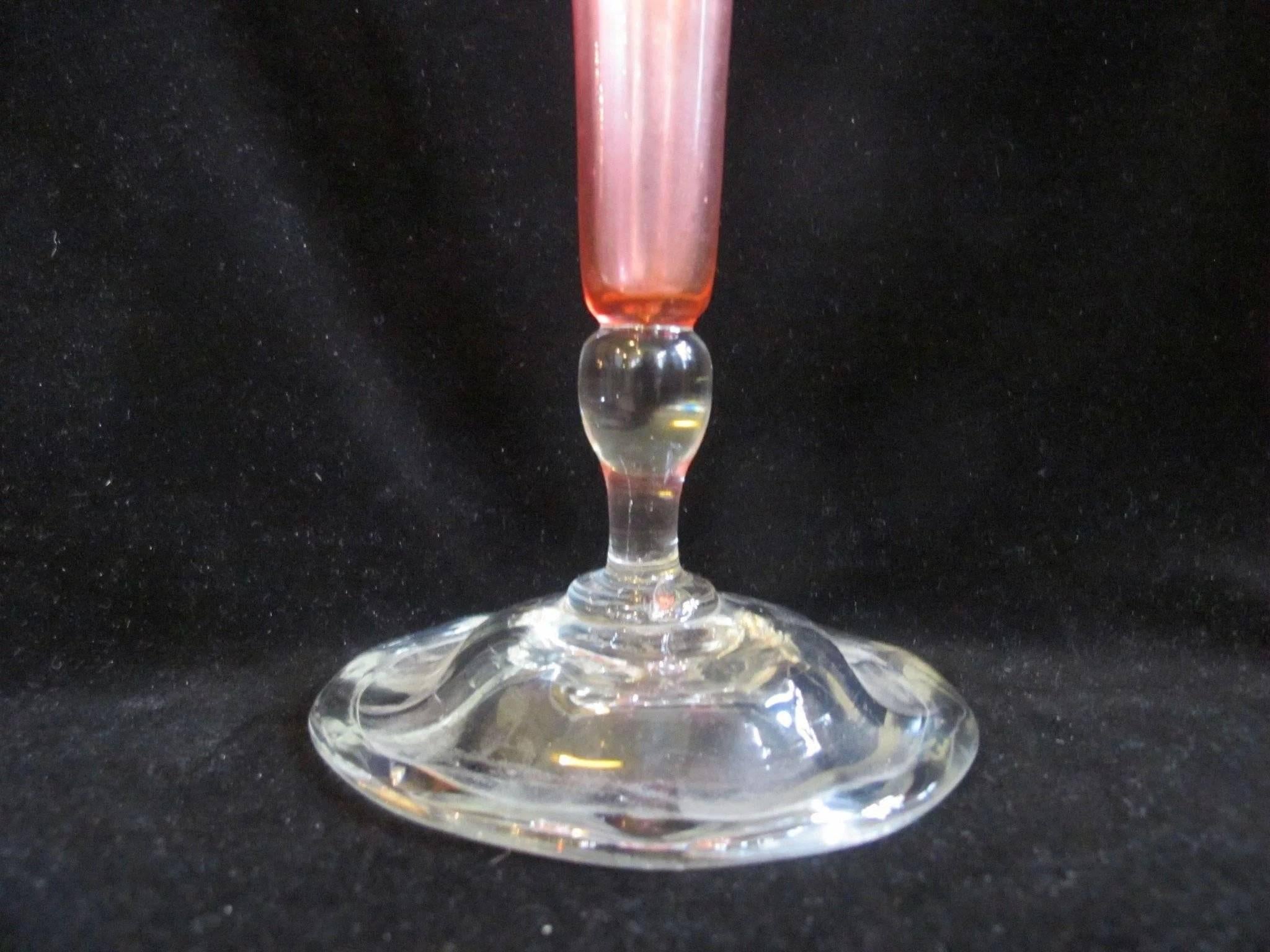 A trumpet shape with a wide flaring rim, tapering to a long slender body on applied clear cushion foot. Pink iridescence shades from slightly gold at the edge of the rim to purple and blue in the body, depending on how the light hits vase. It's an