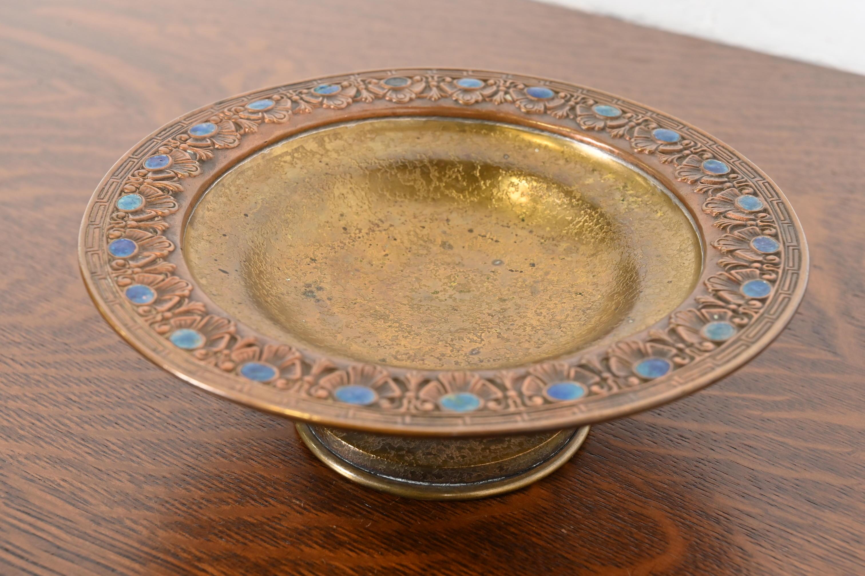 Uno splendido piatto o tazza da centro con piede in bronzo dorato del periodo Arts & Crafts o Art Deco con decorazioni gioiello smaltate

Di Louis Comfort Tiffany Furnaces Inc. (firmato sul lato inferiore)

New York, USA, anni '20

Misure: 8,25