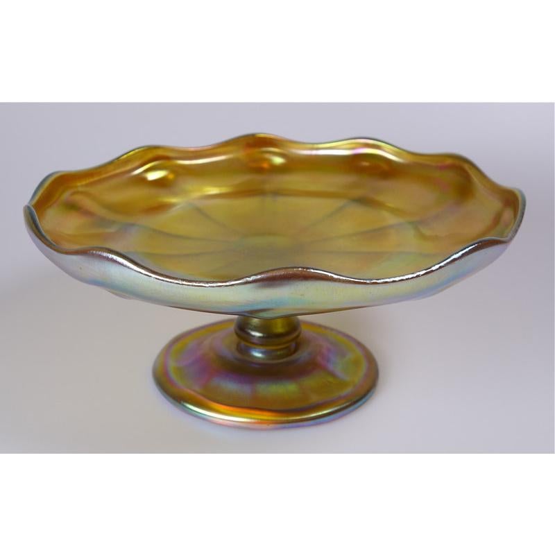 Offering this fabulous Louis Comfort Tiffany gold Favrile iridescent art glass compote or footed dish. This compote features a ribbed dish with a fluted edge attached to a bulbous stem and ribbed round foot. Signed on the underneath 