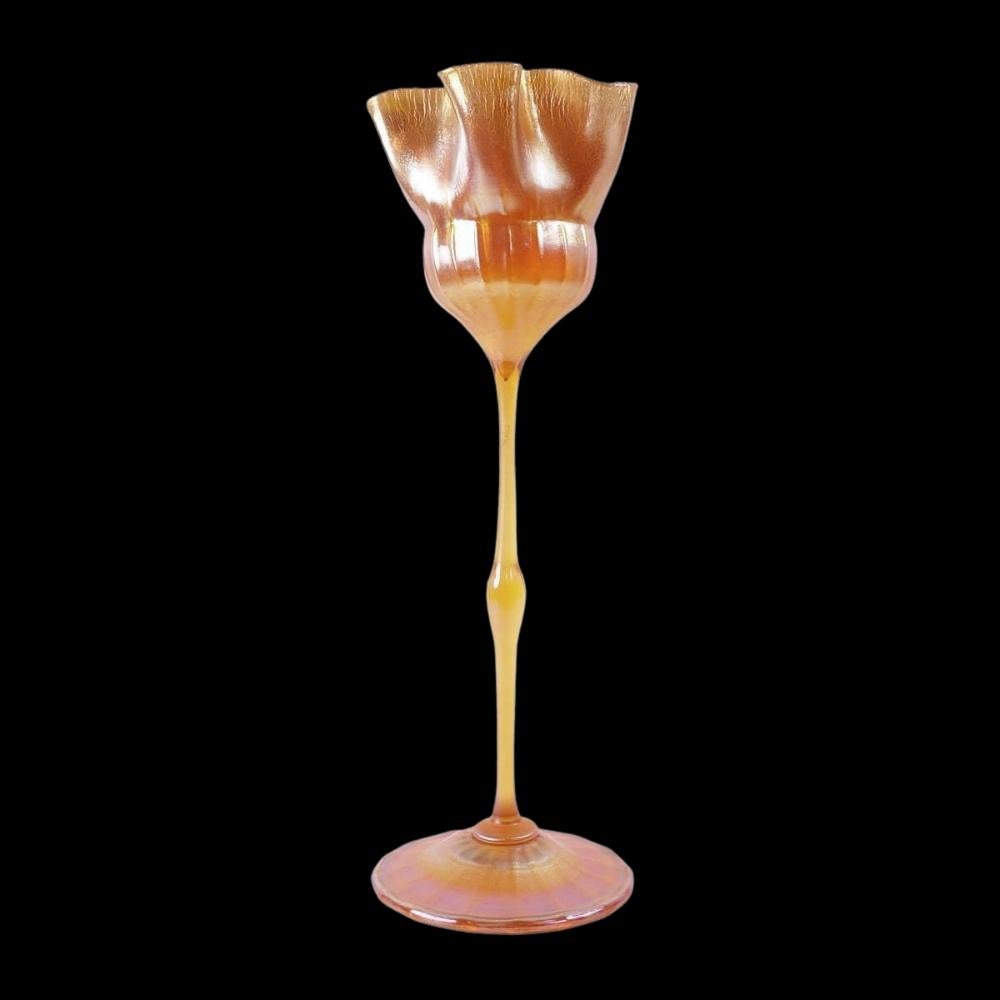Offering this monumental Louis Comfort Tiffany gold Favrile iridescent art glass footed floriform vase. This large vase features a folded, ruffled vessel held by a long, thin stem with applied ribbed round foot. Signed on the underneath 