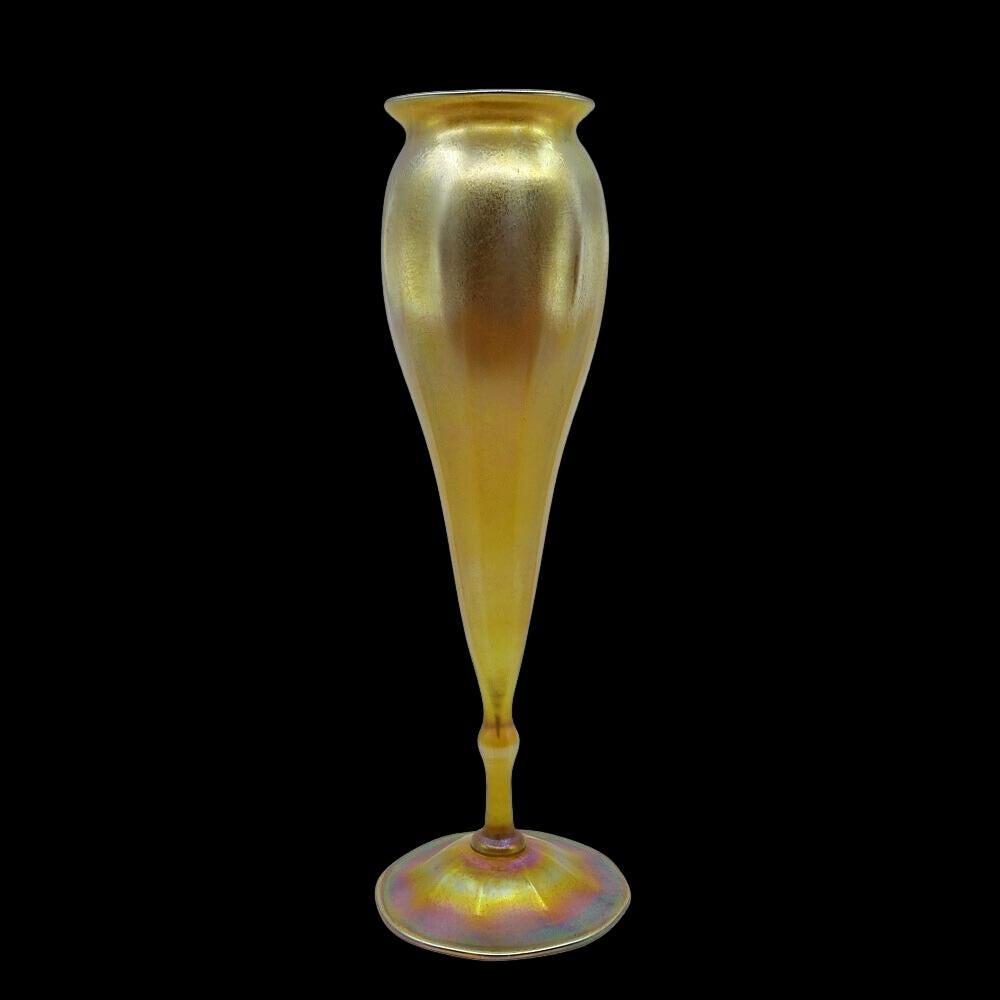Offrant ce monumental vase floriforme à pied en verre d'art irisé Favrile doré de Louis Comfort Tiffany. Ce grand vase présente un corps conique, nervuré et effilé avec une tige fine sur une base à pied rond et une lèvre évasée. Signé en dessous