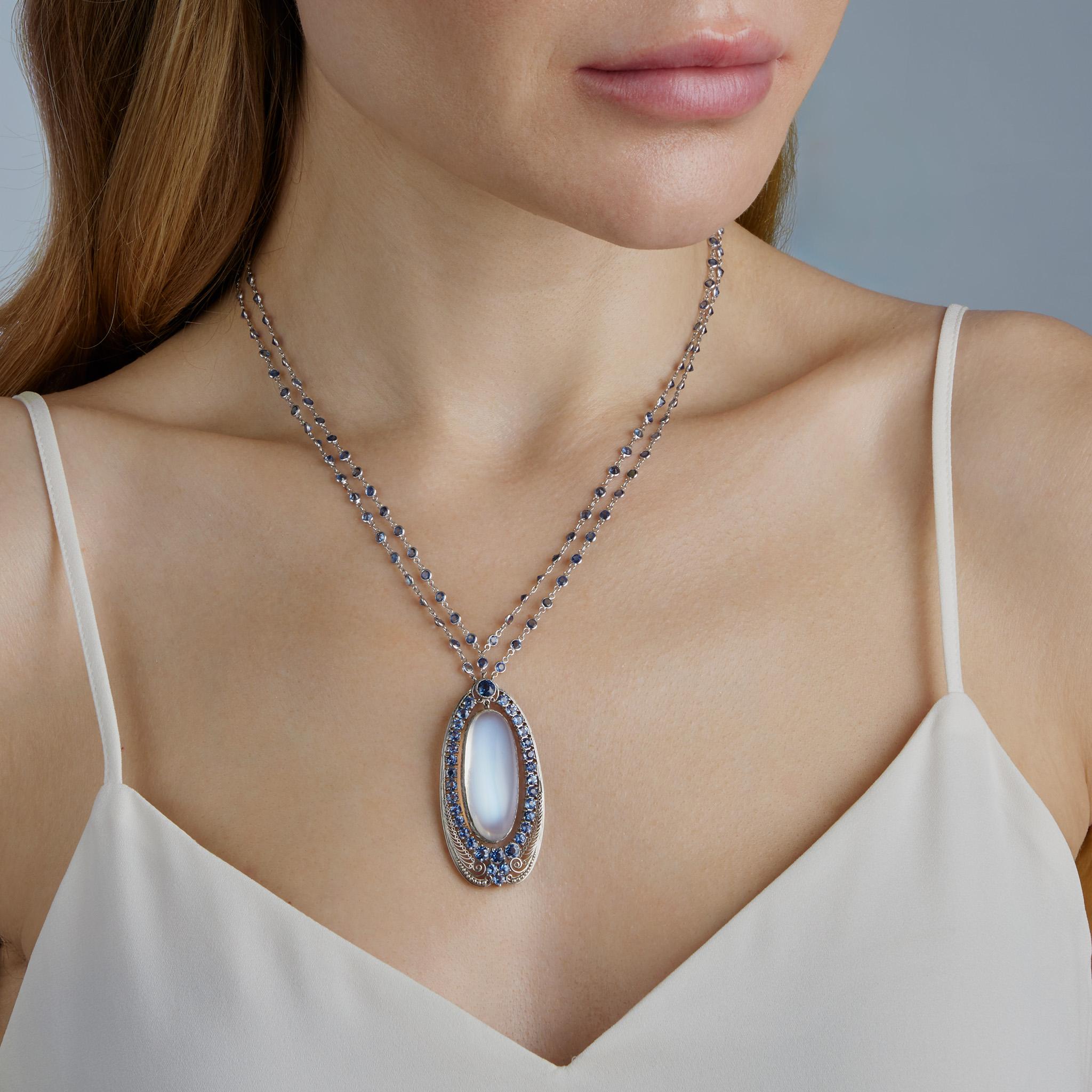 Designed and fully hand created by Louis Comfort Tiffany and his jewelry studio between approximately 1910 and 1920, this moonstone, sapphire and platinum pendant hangs from a later sapphire chain. The pendant is designed as an elongated teardrop