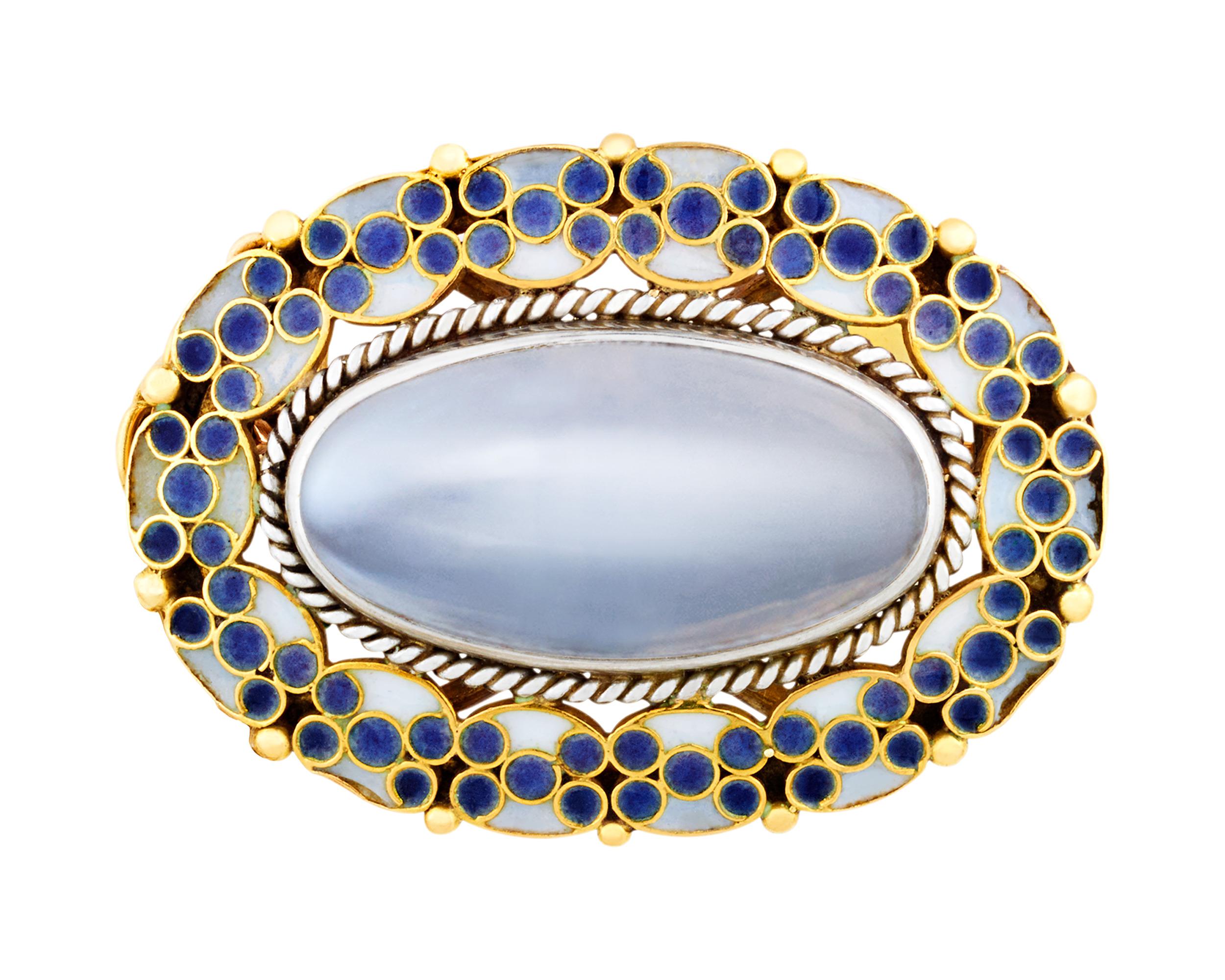 This exquisite pendant and brooch by Louis Comfort Tiffany for Tiffany & Co. is a triumph of Art Nouveau design. At its heart lies a captivating cabochon moonstone totaling 9.00 carats, its soft iridescent blue glow haloed by intricate plique-à-jour