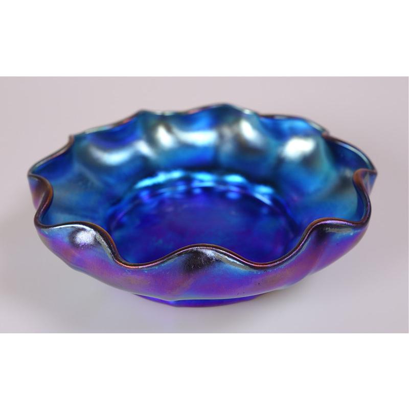 Offering this rare Louis Comfort Tiffany blue Favrile iridescent art glass bowl. This blue finger or berry bowl features a undulating ribbon design lip and is signed on the underneath 