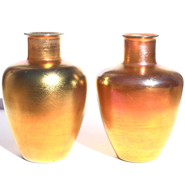Pair Tiffany gold favrile glass vases.

Both shouldered urn form vases in iridescent gold Favrile glass. Very rare to find a pair of these wonderfully sized favrile Tiffany vases. Both have their own characteristics one showing more red than the