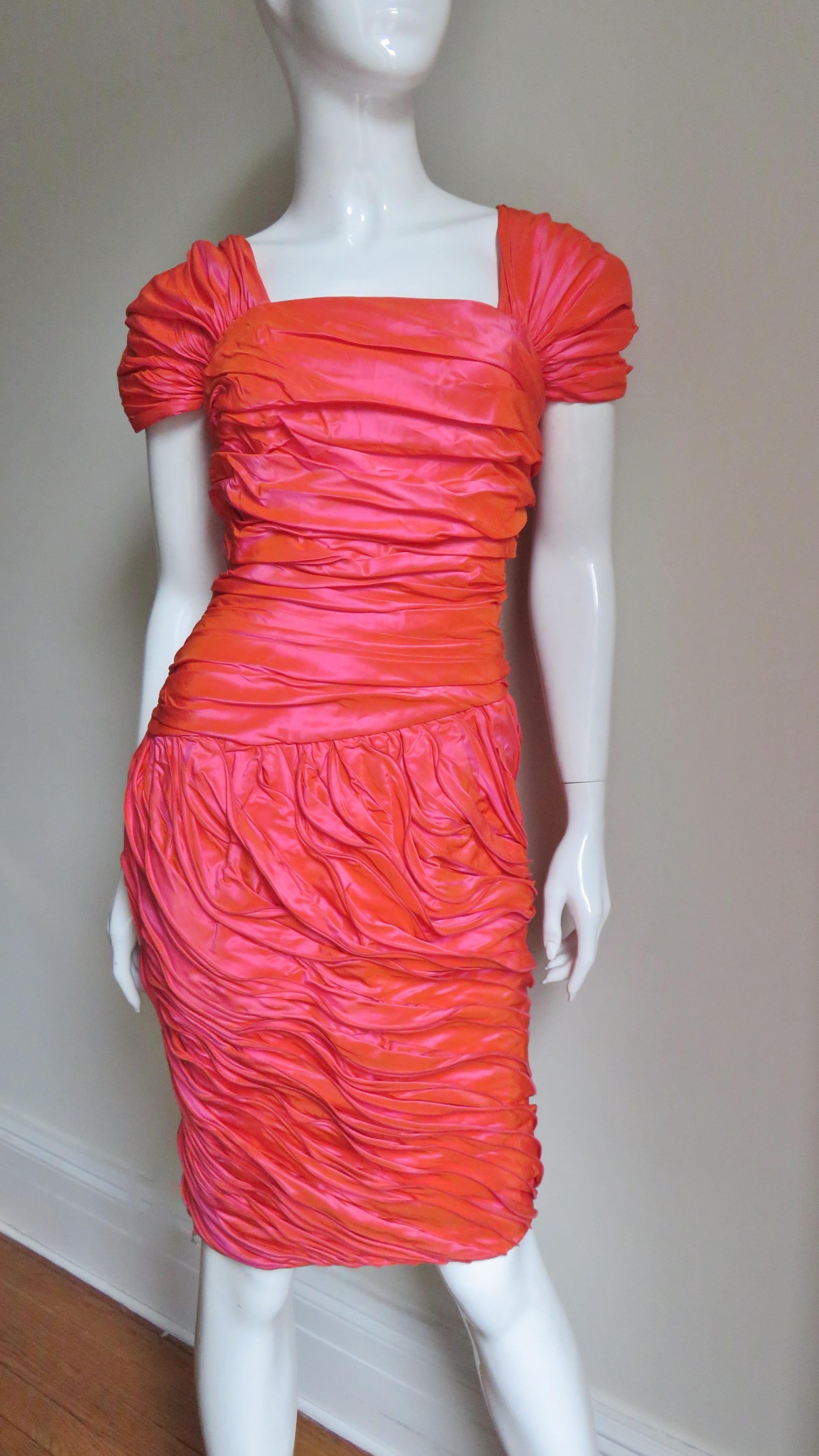 A gorgeous coral silk dress from Louis Feraud.  The silk has a slight iridescent quality alternating subtly between shades of coral and rose coral. The dress has gathered cap sleeves over the shoulders and ruching across the bodice front and back.