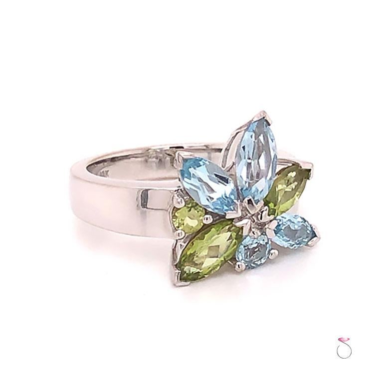 French Designer Louis Feraud Aquamarine and Peridot Cluster Ring in 18k white gold. This beautifully designed ring features a gorgeous cluster of gemstones different shapes and colors. The gemstones are marquise and round brilliant cuts and have